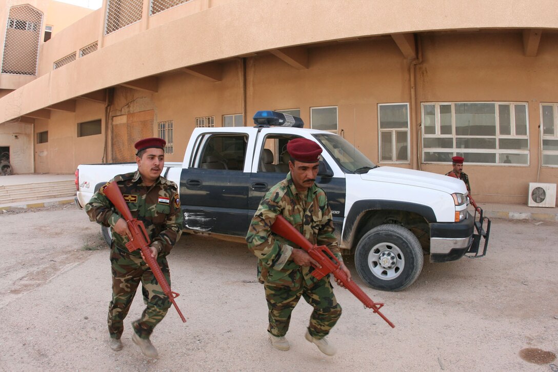 Sgt. Ammar Muhammed Hammed (left), a 25-year-old Fallujah native, and Warrant Officer Hashim Fakri Hasan, 36, of Najaf, practice rushing from their vehicle to help establish a "security bubble" during a personal security detail training session that was lead by the Trebil Port of Entry Transition Team Oct. 13.  The PSD's primary mission is to ensure the safety of the port deputy director and any visiting dignitaries here.::r::::n::