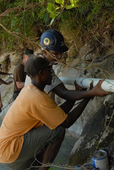 BAINET, Haiti -- Senior Airman Joseph Joiner, 5th Civil Engineer Squadron Prime Base Engineer Emergency Force heating, ventilation, air conditioning journeyman,  works with a local Haitian man while reconstructing a water pipe which was destroyed in recent storms. Airman Joiner, along with other Airmen from Minot AFB's 5th CES, is currently embarked aboard USS Kearsarge (LHD 3) in support of Continuing Promise 2008. CP 2008 is a collaborative effort between the United States and partner militaries, non-governmental organizations, and partner-nation support organizations to build strong partnerships that can be called upon in the event of a regional situation requiring cooperative solutions. (U.S. Navy photo by Mass ?Communication Specialist 2nd Class (AW/SW) Gina Wollman)
