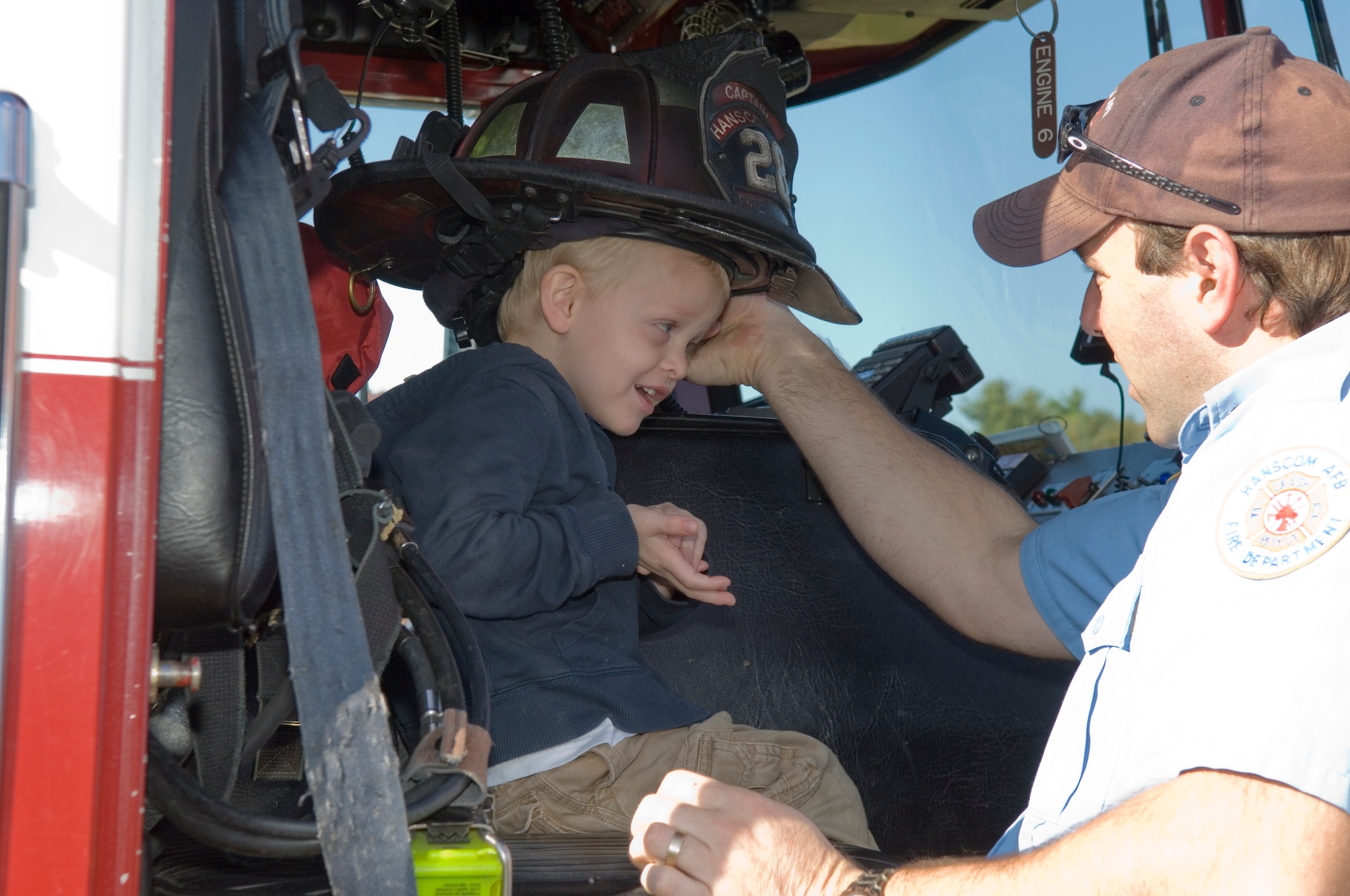 HANSCOM AFB, Mass. – Anthony Legrow (left), tries on a fire helmet with the assistance of Hanscom Fireman Mick Sanchez on Oct. 9. The Hanscom Fire Department visited the Child Development Center as well as other locations on base in celebration of Fire Prevention Week.  (U.S. Air Force photo by Rick Berry)