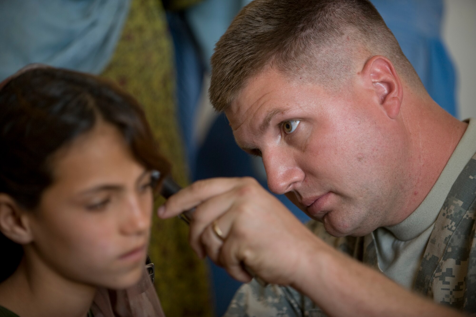 QALAT, Afghanistan -- Capt. (Dr.) James Arnold,  Zabul Provincial Reconstruction Team, examines an Afghan girl complaining of an ear ache during a Women's Village Medical Outreach visit. In a country where women are not typically seen by male doctors, the PRT examined more than 60 women. Dr. Arnold is a family practice doctor deployed to the PRT from Anderson Air Force Base, Guam.(U.S. Air Force photo/Master Sgt. Keith Brown)