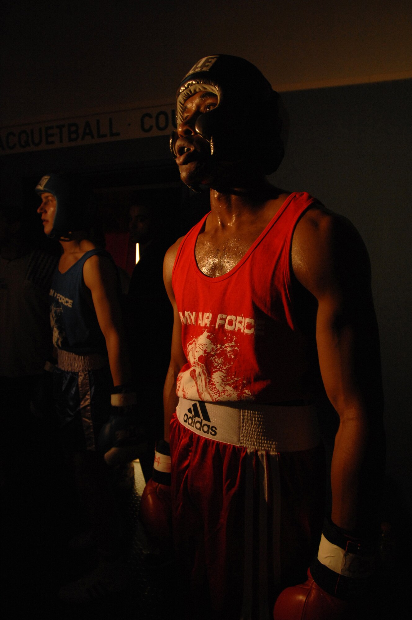 United States Air Force Staff Sgt. Harold Davis (red trunks), 86th Maintenance Squadron, Ramstein Air Base, and Denis Heier (blue trunks), a German boxer from the Turngemeinde Boxing Club, watches in the shadows prior to a boxing match, Vogelweh Air Base, Germany, Oct. 11, 2008 Staff Sgt. Davis lost his match against Heier. (U.S. Air Force photo by Senior Airman Amber Bressler)(Released)