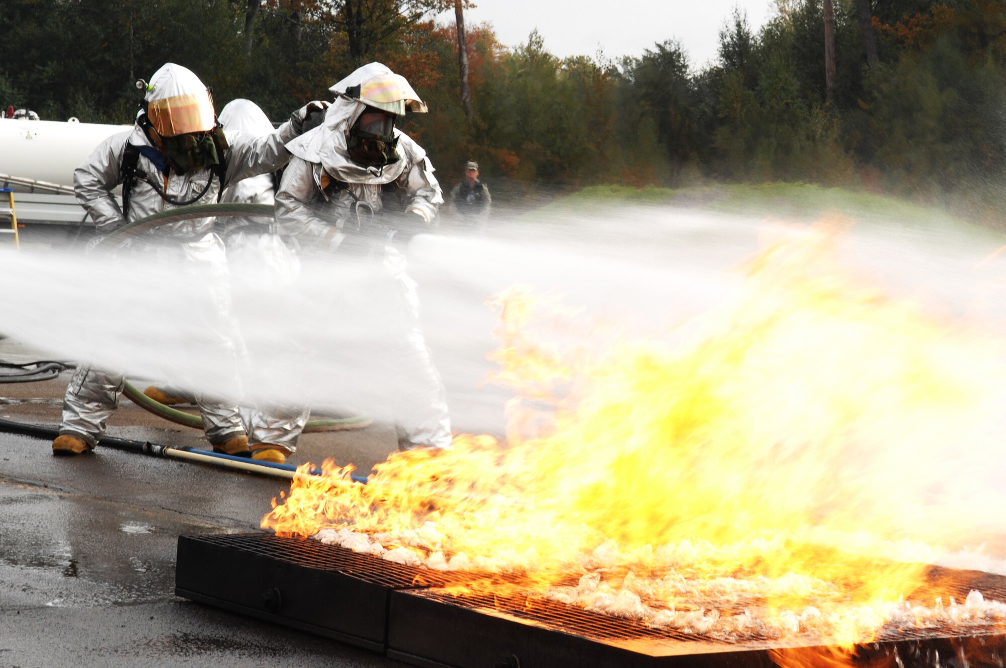 United States Air Force firefighters participate in live-fire training on the Mobile Aircraft Fire Trainer in support of the Silver Flag exercise 09-01, Ramstein Air Base, Germany, Oct. 9, 2008. Silver Flag provides expeditionary combat support training to Airmen in the civil engineer, personnel services, contracting and services career fields, preparing them for upcoming deployments. (U.S. Air Force photo by Senior Airman Amber Bressler)(Released)*