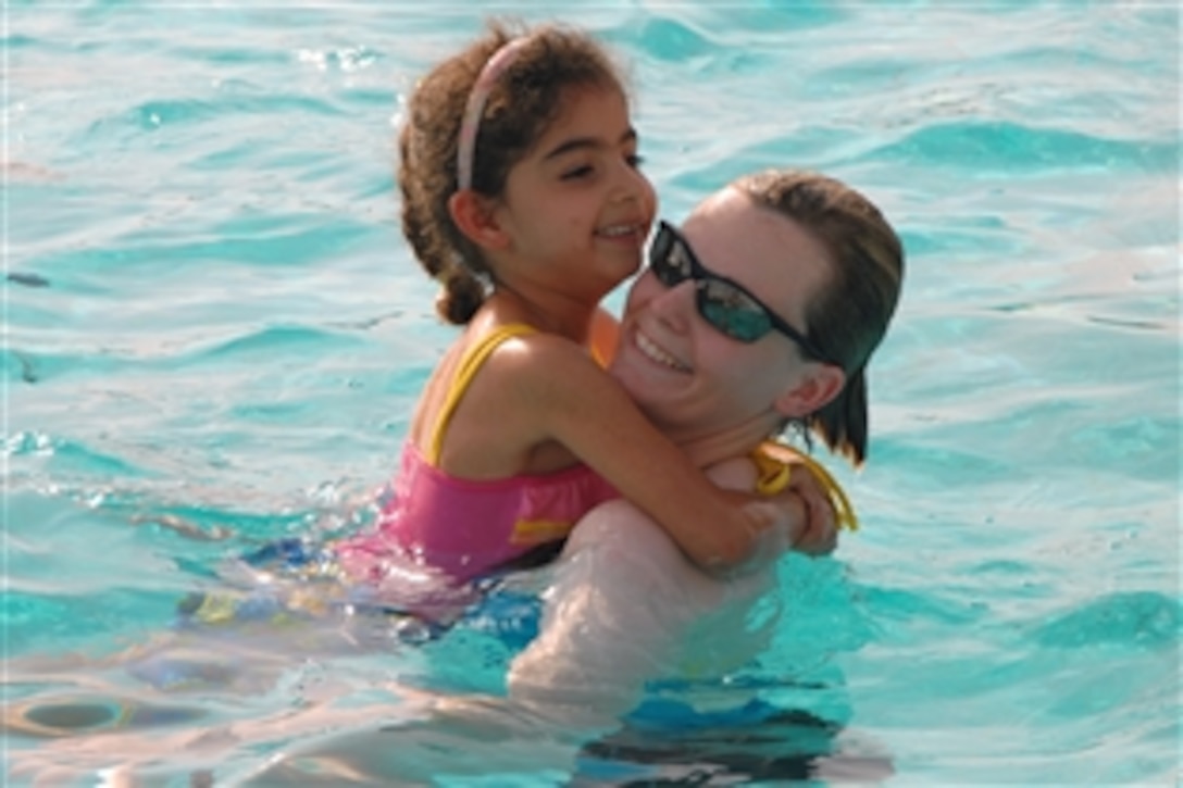 U.S. Army 1st Lt. Stephanie Flowers swims in the Australian swimming pool with an Iraqi girl scout during a visit on Camp Victory, Baghdad, Iraq, Oct. 11, 2008. 