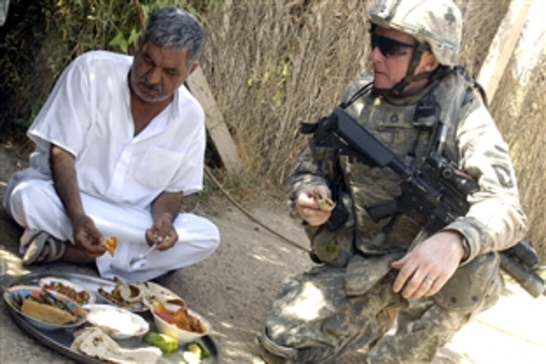 U.S. Army Staff Sgt. Michael Hall stops for a snack with a local Iraqi man while clearing the Owja Desert of Iraq, Oct. 10, 2008. The soldiers are assigned to the 1st Brigade Combat Team, 327th Infantry Division, 101st Airborne Division.