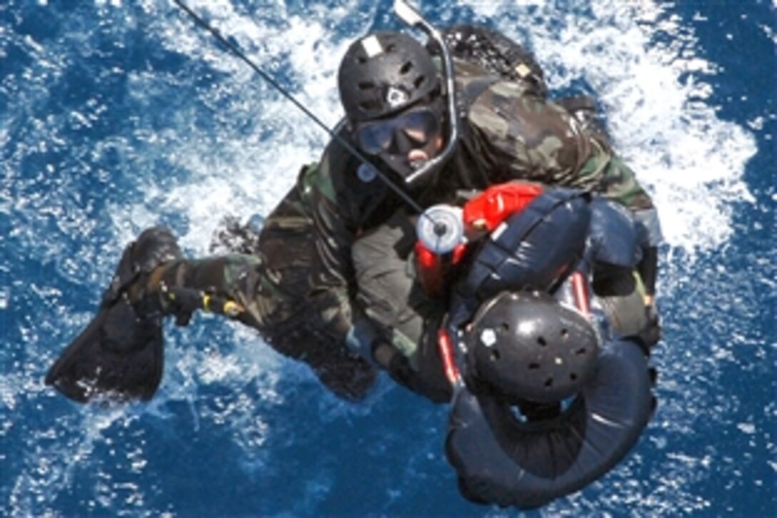 U.S. Air Force Senior Airman Oliver Smith and a "downed" F-15 Eagle pilot are hoisted out of the water into a HH-60G Pave Hawk during a crisis management exercise off the coast of Okinawa, Japan, Oct. 8, 2008. Members of the 18th Wing from Kadena Air Base, Japan, and the Japanese coast guard rehearsed response procedures for a simulated over the water aircraft accident. Smith is a pararescue airman assigned to the 31st Rescue Squadron.