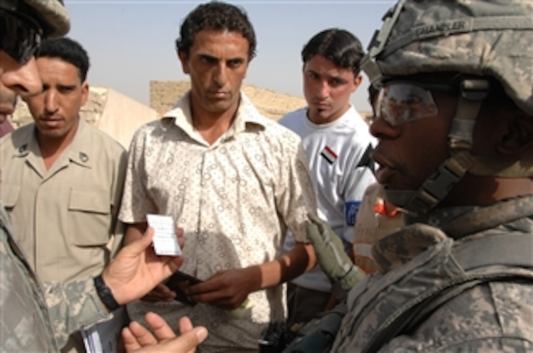 U.S. Army Maj. Malcolm Chandler of the 1-8-2 National Police Transition Team, 4th Brigade Combat Team, 10th Mountain Division talks to some off duty Iraqi National Police about identification card replacement needs at their outpost outside Forward Operating Base Loyalty in eastern Baghdad, Iraq, on Oct. 7, 2008.  