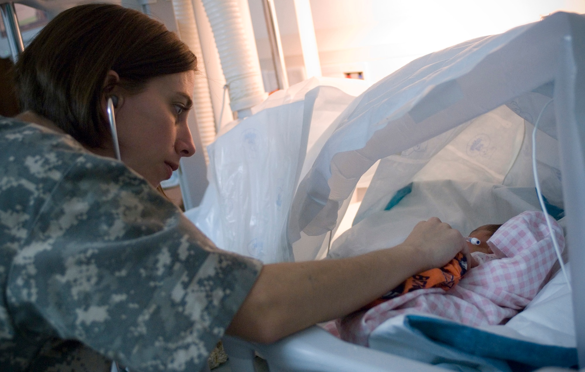 First Lt. Michelle Pierson, an Intensive Care Unit nurse deployed from Travis Air Force Base, Calif., listens to the heartbeat of the first Afghan baby born at the Craig Joint Theater Hospital, Bagram Air Field, Afghanistan, Oct. 6. Without typical neonatal equipment on hand, the hospital staff created a makeshift incubator with a warming blanket and wire hangars. (U.S. Air Force photo by Staff Sgt. Rachel Martinez)