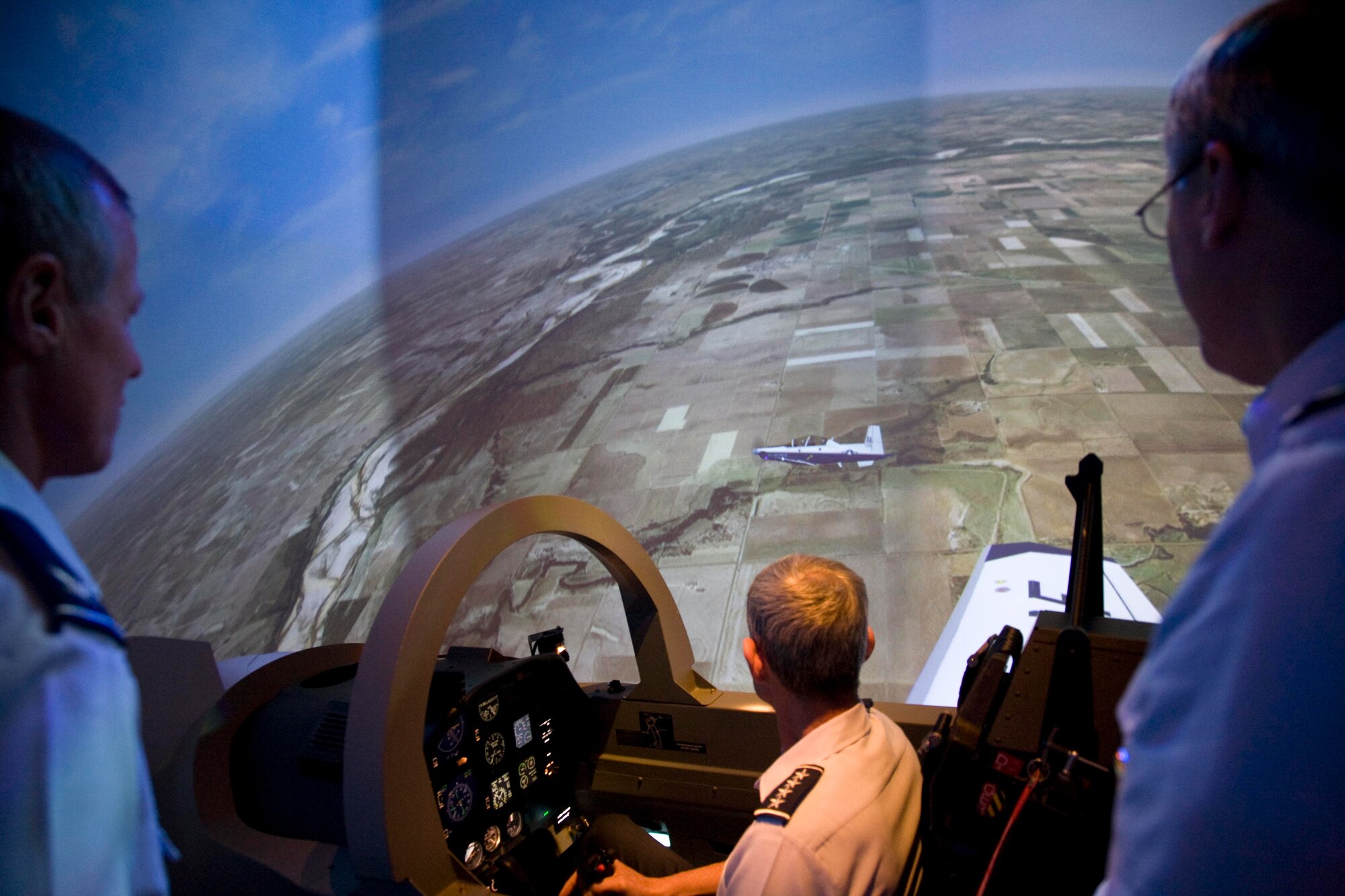 While Brig. Gen. O. G. Mannon, 82nd Training Wing commander, looks on, Col. David Petersen takes full advantage of the increased fidelity of the T-6 simulator by instructing Gen. Norton Schwartz, Chief of Staff of the Air Force, on the basics of flying formation in the T-6 Texan II during the NATO Air Chiefs Visit Oct. 9. (U.S. Air Force photo/Lt. Col. Ternell Washington)