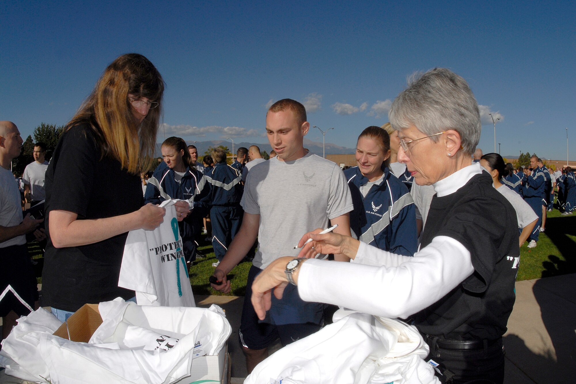 Ms. Jeanine Arnold, Peterson's Sexual Awareness Response Coordinator and Ms. Kathy Nelson of the 21st SW Staff Judge Advocate Office pass out team leader t-shirts prior to the Amazing Wingman Race.  The day was full of briefings, education, and field games to remind Peterson Airman how to be a good wingman. The Air Force established the Wingman program to encourage Airmen and their families to look out for each other and to intervene when signs of stress are observed. It's a promise, a pledge, a commitment between Airmen to cover each other when an airman may be in need of assistance. (Air Force photo/Rob Bussard)