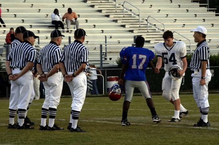 Football official Rocky Huggins has the team captains from the Colleton County High School and Fort Dorchester High School freshman teams shake heads as officials Scott Vendrely, Ed Ebersole, Sean Houlihan and Randall Edwards observe in North Charleston, S.C., Oct. 2. The officiating crew is made up of Airmen or former Airmen who give back to the community through officiating high school, middle school and recreation department football games.  (U.S. Air Force photo/Airman 1st Class Timothy Taylor)