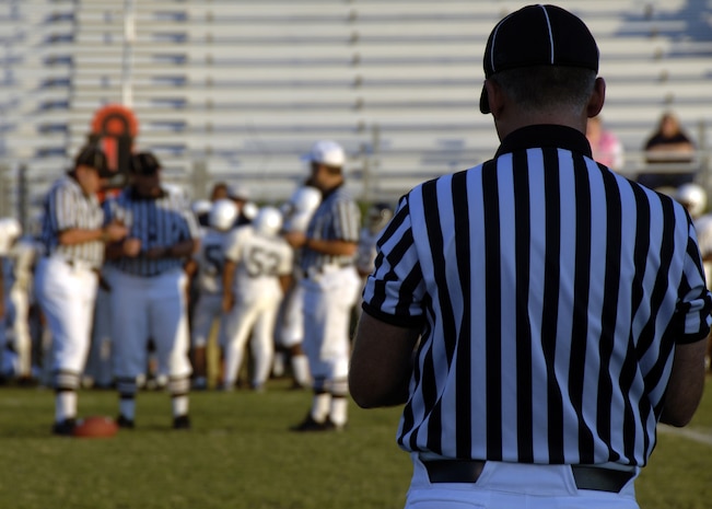 Randall Edwards watches as officials Scott Vendrely, Ed Ebersole and Rocky Huggins confer in the middle of the field during the Colleton County High School and Fort Dorchester High School freshman game in North Charleston, S.C., Oct. 2. The five-man crew of officials is made uip of Airmen or former Airmen who give back to the community through officiating high school football games. (U.S. Air Force photo/Airman 1st Class Timothy Taylor)
