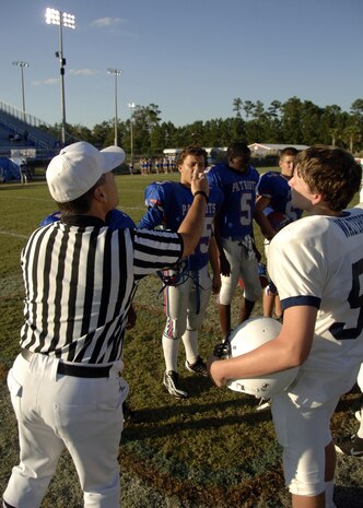 Rocky Huggins tosses a coin with team captains to determine which team will receive the kickoff during the Colleton County High School and Fort Dorchester High School freshman game in North Charleston, S.C., Oct. 2. The officiating crew is made up of Airmen or former Airmen who give back to the community through officiating high school, middle school and recreation department football games. Huggins is a reservist with the 315th Civil Engineer Squadron at Charleston AFB.  (U.S. Air Force photo/Airman 1st Class Timothy Taylor)