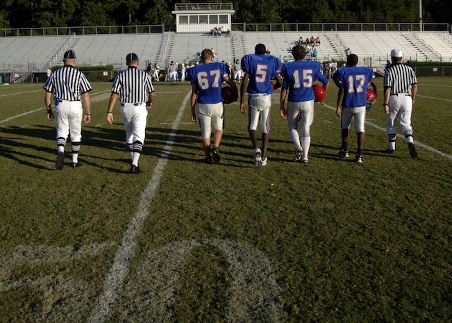 From left to right, football officials Sean Houlihan, Randall Edwards and Rocky Huggins escort Fort Dorchester High School team captains for the coin toss before a freshman game in North Charleston, S.C., Oct. 2. The officiating crew is made up of Airmen or former Airmen who give back to the community through officiating high school, middle school and recreation department football games. The three officials are all Airmen assigned to Charleston AFB.  (U.S. Air Force photo/Airman 1st Class Timothy Taylor)