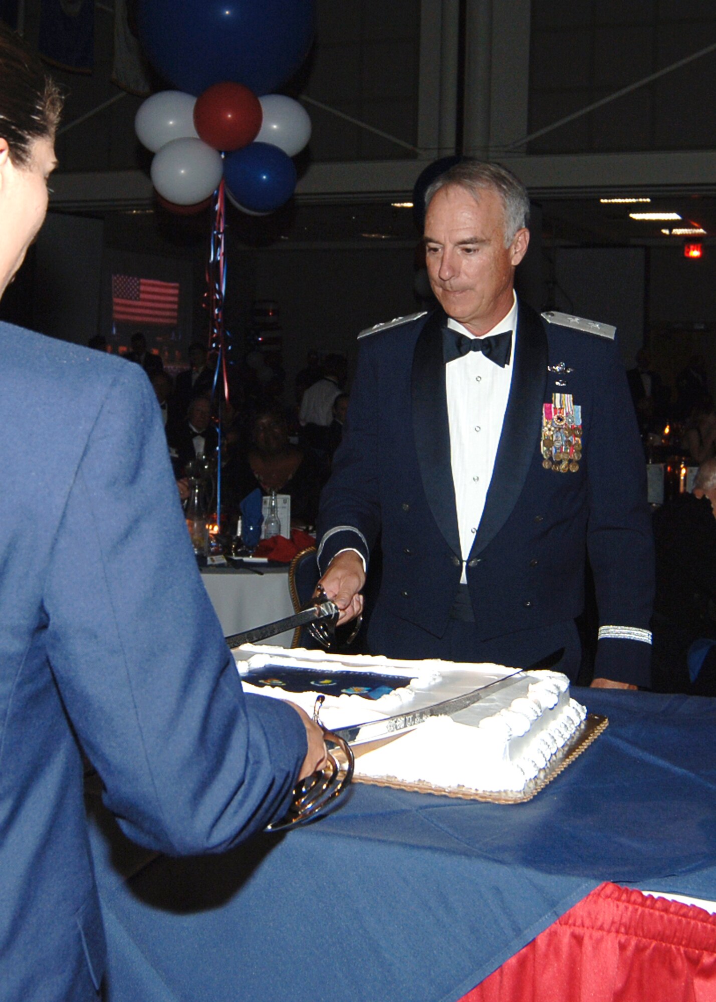MCCONNELL AIR FORCE BASE, Kan. -- Maj. Gen. Winfield Scott III, 18th Air Force Commander, and Airman Basic Stephanie Savaiano, 22nd Aerospace Medical Dental Squadron, make the initial cut into one of the Air Force Ball cakes using sabres during the cake cutting ceremony, Oct. 10.  (Photo by Airman 1st Class Maria Ruiz)