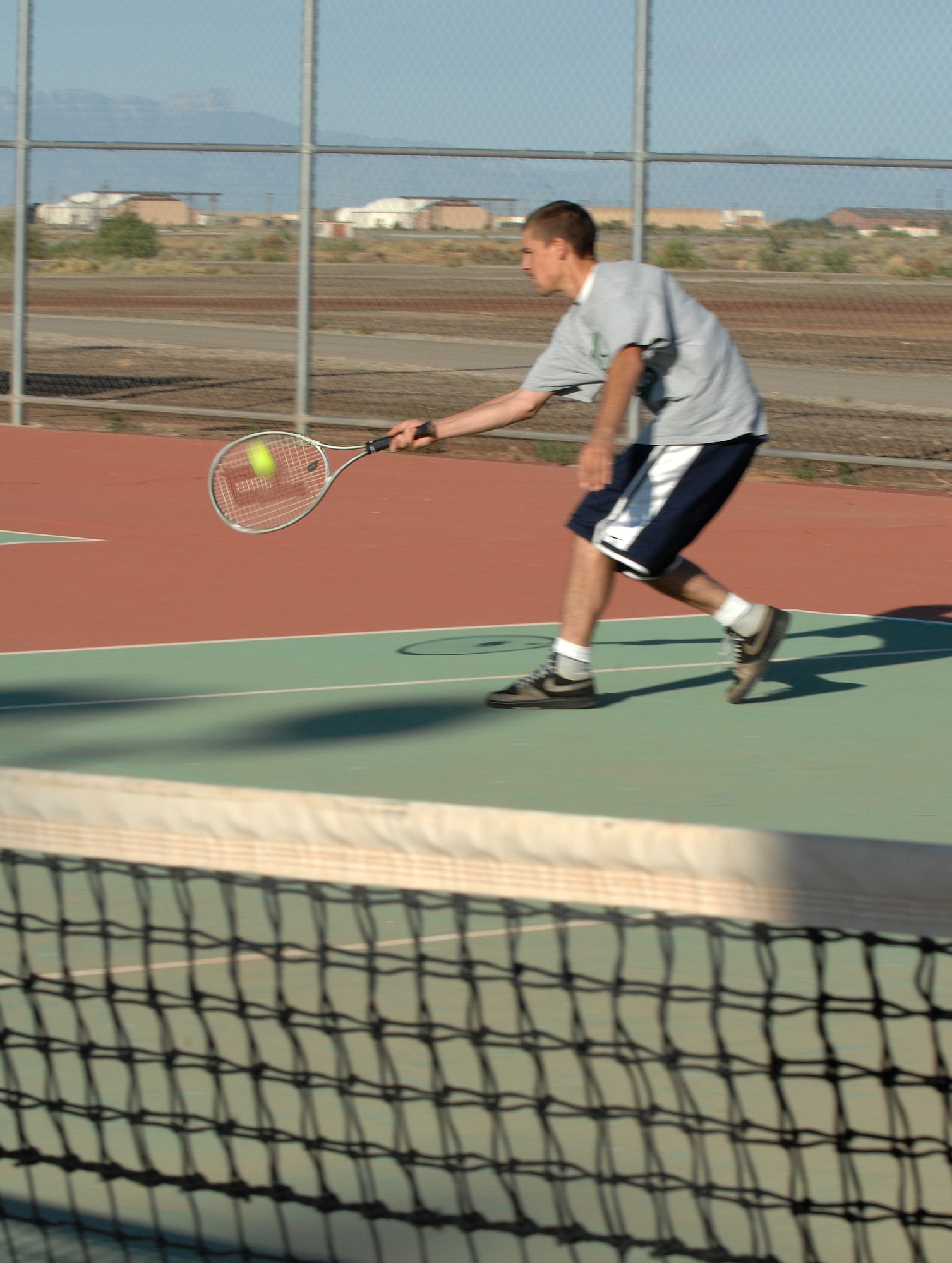 Airman 1st Class Miles Mendez, 49th Materiel Maintenance Group, reaches to hit the tennis ball during his match against Capt. Chris Rosales, 49th Logistics Readiness Squadron, on Sports Day at Holloman Air Force Base, N.M., October 10. More than 20 tennis players participated in the competition. (U.S. Air Force photo/Airman Sondra M. Escutia)