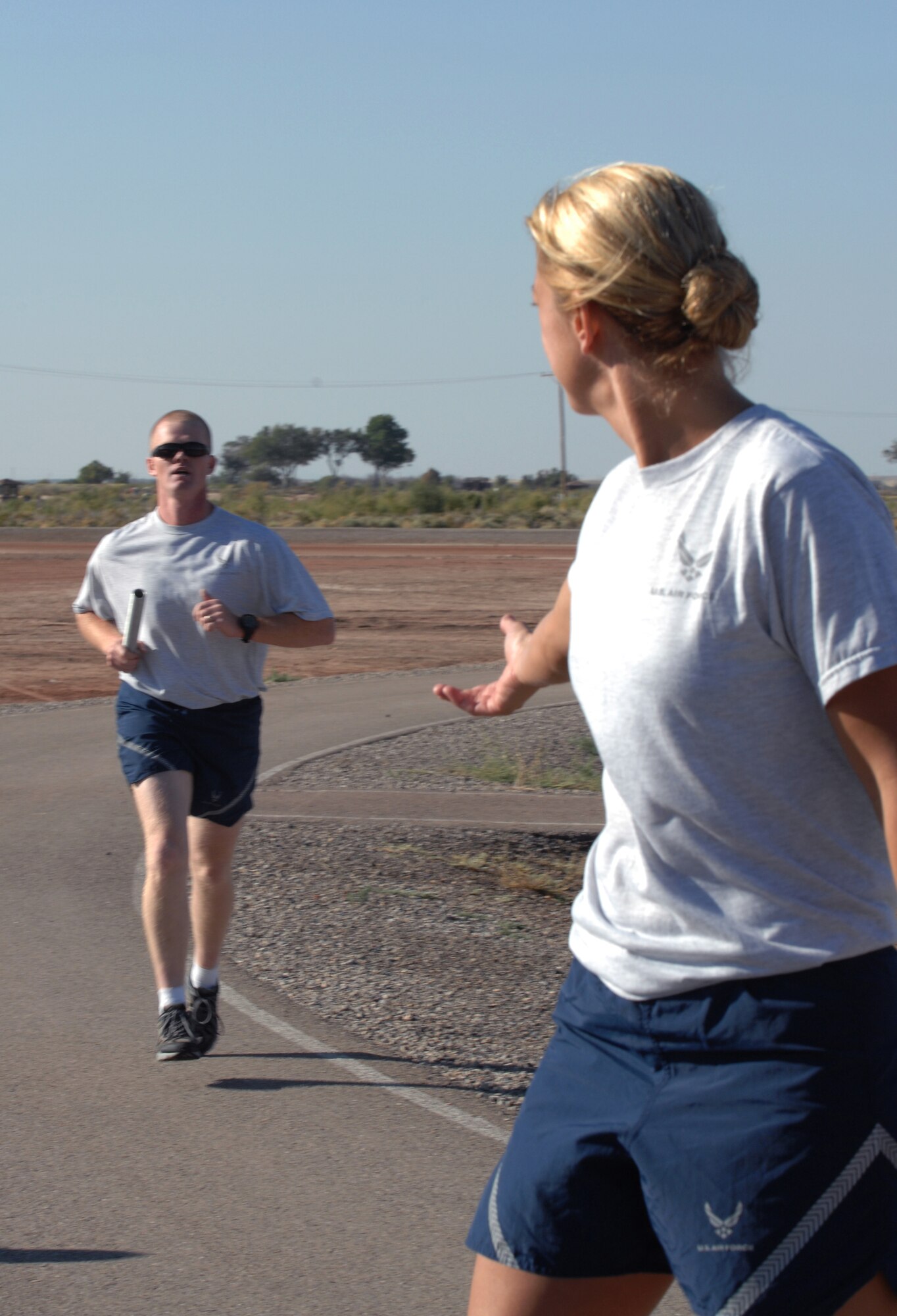 Tech. Sgt. Brady McCoy, 49th Security Forces Squadron, finishes up his run and prepares to hand off the baton to Tech. Sgt. Heather Huckins, also 49th SFS, during the three-mile-relay on Sports Day at Holloman Air Force Base, N.M., October 10. (U.S. Air Force photo/Airman Sondra M. Escutia)