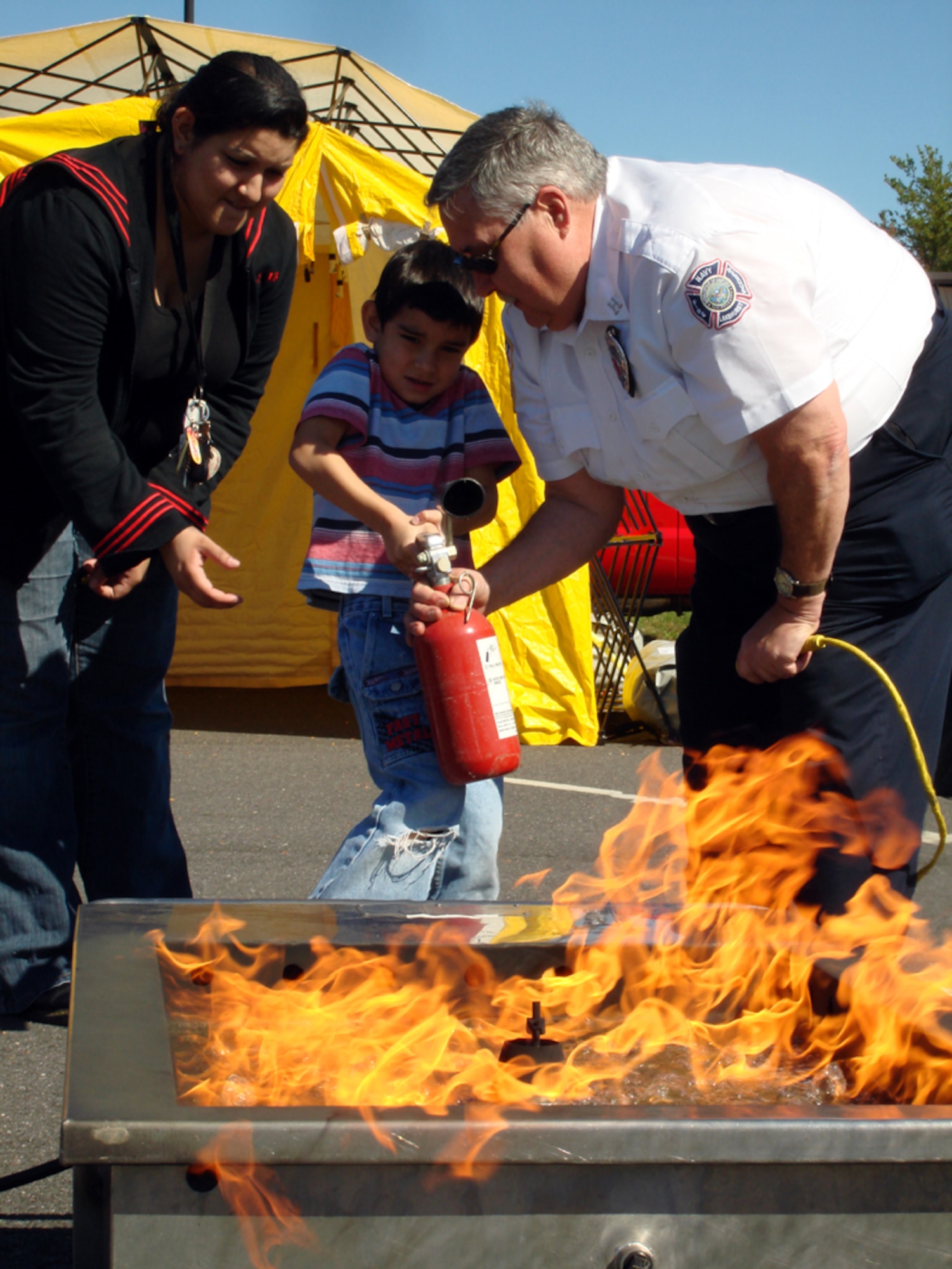To close out Fire prevention week, James Quinn, Lakehurst Fire inspector, shows Team McGuire families how to use a fire extinguisher Oct. 11 in the BX parking lot. Mr. Quinn discussed the importance of fire prevention and gave participants the chance to test their skills at putting out fires. The McGuire, Fort Dix and Lakehurst Fire Departments hosted the hands-on event. (U.S. Air Force photo/Staff Sgt. Francis Lalic)