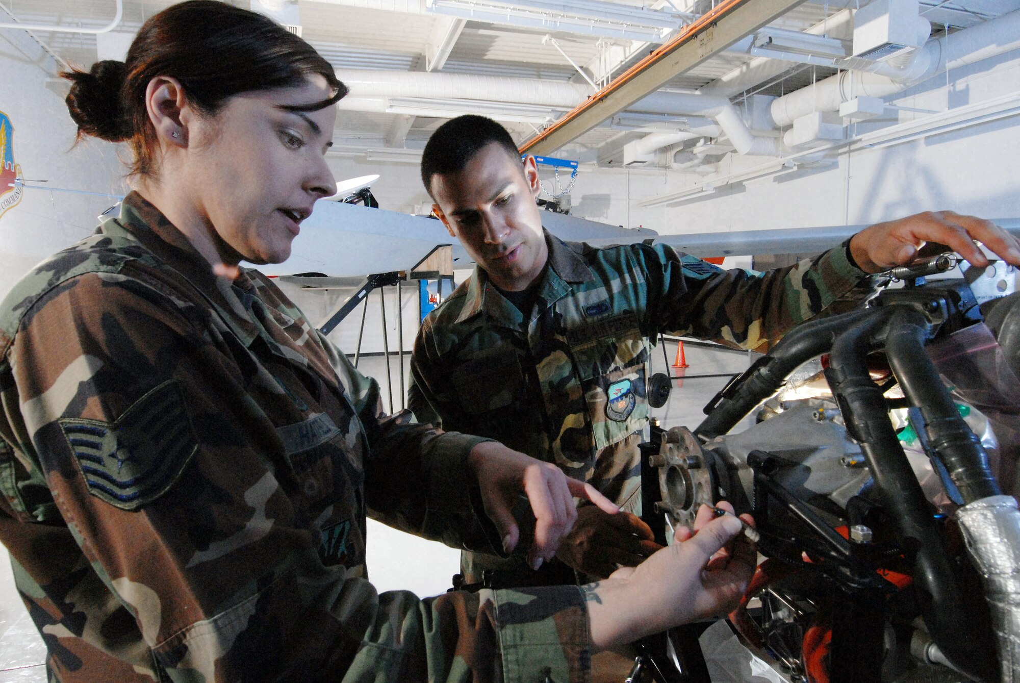 Tech. Sgt. Rebecca Hatfield (left), an instructor with Field Training Detachment 26 of the California Air National Guard's 163rd Maintenance Group, shows the components of the engine of an MQ-1 Predator unmanned aircraft to Staff Sgt. Carlos Barrera Oct. 15.  Sergeant Barrera is a crew chief with the 163rd Reconnaissance Wing at March Air Reserve Base, Calif.  Airmen with Det. 26 train active duty, Reserve and Air National Guard personnel on Predator maintenance operations. (U.S. Air Force photo/Senior Airman Matt Smith)
