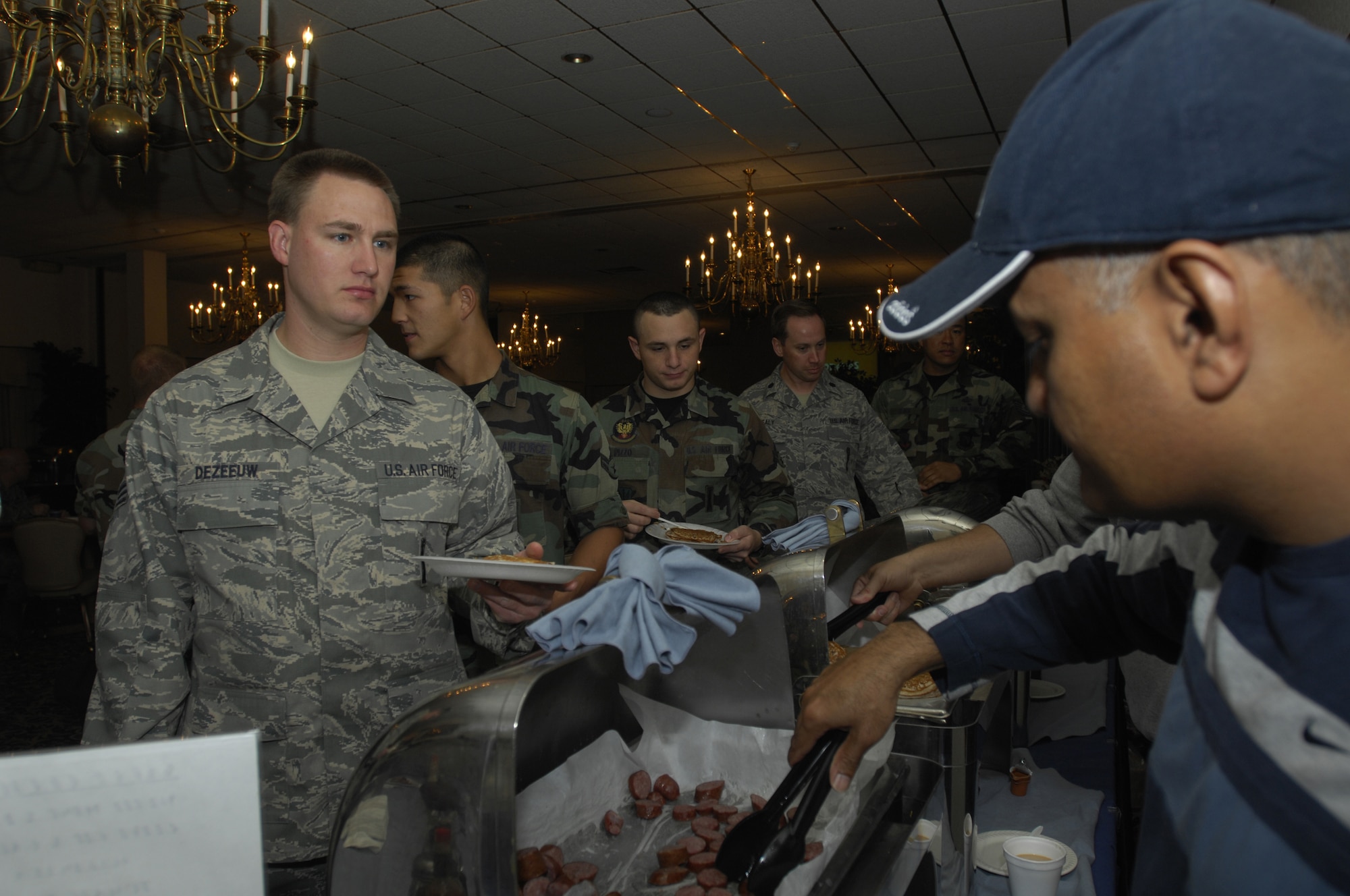MINOT AIR FORCE BASE, N.D. -- Senior Airman Rick Dezeeuw, 91st Missile Maintenance Squadron, receives cut sausage served by Chief Master Sgt. Mark Budhoo, 5th Aircraft Maintenance Squadron, during the Minot Chief's Group sponsored pancake breakfast at the Jimmy Doolittle Center here Oct. 10.  The chief's group provides the pancake breakfast twice a year to Minot AFB’s Airmen and their families. (U.S. Air Force photo by Airman 1st Class Jesse Lopez)