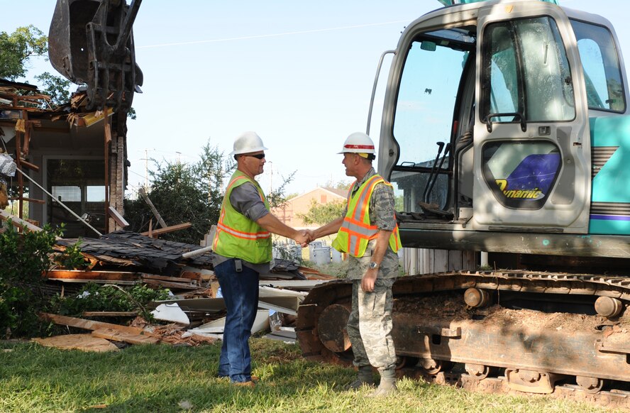 DYESS AIR FORCE BASE, Texas -- Colonel Robert Gass, 7th Bomb Wing commander, shakes the hand of a contractor and thanks him for his help after participating in the demolition of the previously designated wing commanders house here, Oct. 10.  This house is one of the last of the old base houses to be demolished.  Dyess AFB has replaced the old housing units with new homes to meet new standards and improve quality of life for our Airmen.  (U.S. Air Force photo/Staff Sergeant Darcie Ibidapo)