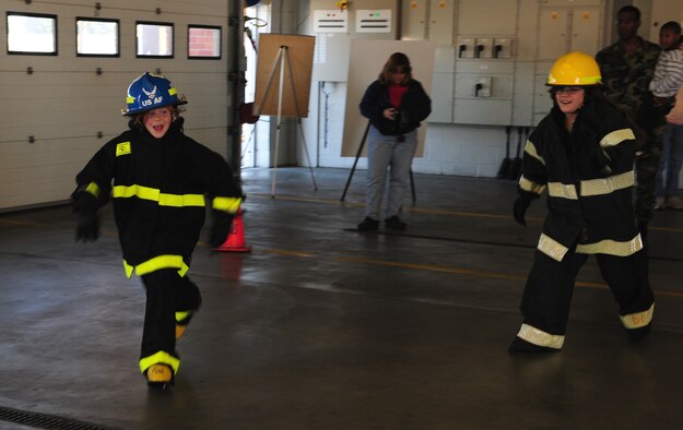Ashli Ayers, left, 10, and Aleyiah Pena, right, 10, take part in the bunker race at the RAF Mildenhall Fire Department Oct. 11. The fire station held an open house at the end of Fire Prevention Week and had plenty of events for children, including the bunker race, fire truck demonstrations, chip pan demonstrations, Sparky the Fire Dog and bouncy castles. The firefighters also provided hot dogs and hamburgers, provided by Team 5/6, and there were prize giveaways throughout the day. (U.S. Air Force photo by Karen Abeyasekere)