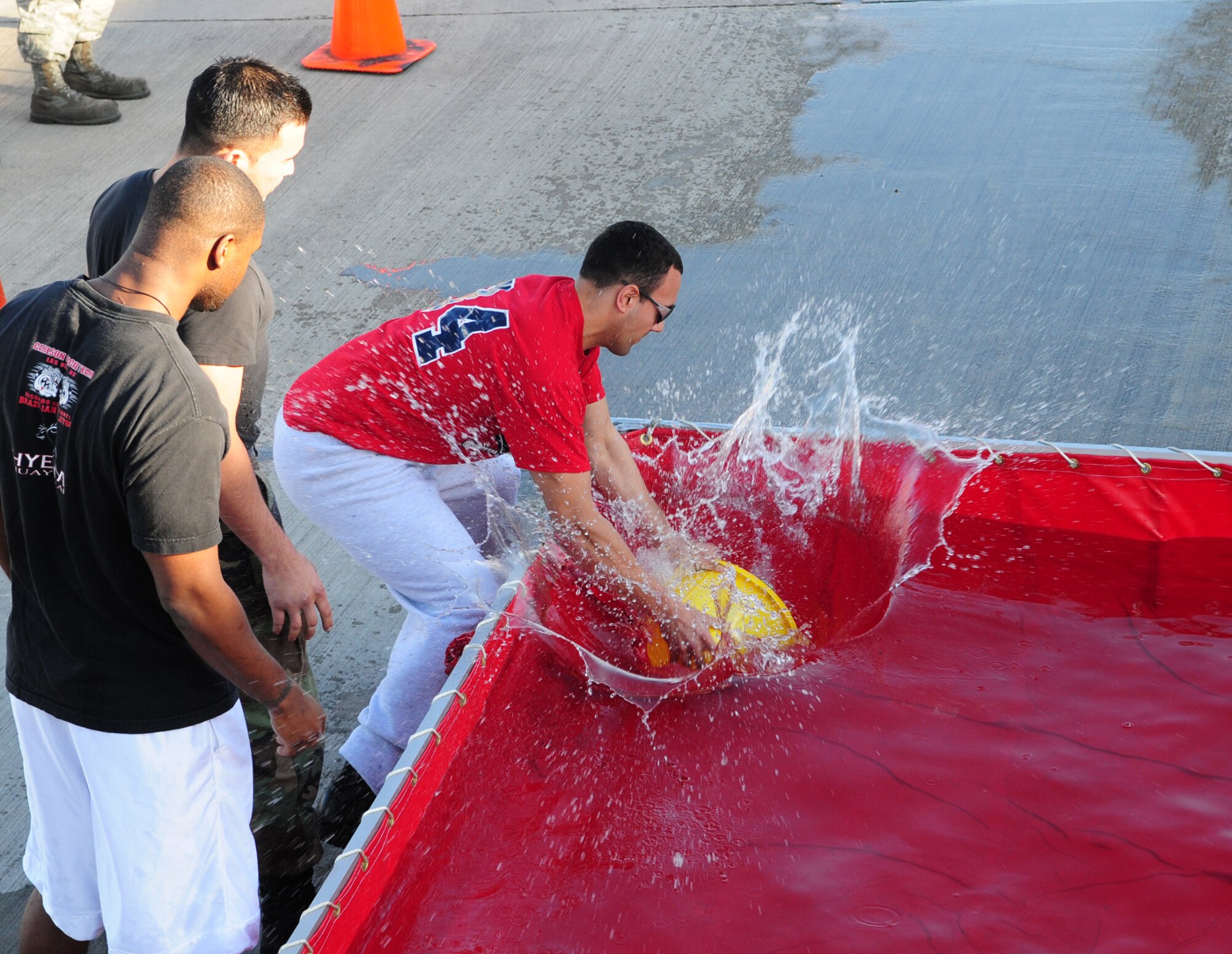 The 100th CES Electricians grab buckets of water from the pool before racing down to throw it on the wooden house during the tiebreaker competition after the fire muster Oct. 9. The firefighter challenge course was open to squadron and flight teams from RAF Mildenhall as part of Fire Prevention Week events. Also at the event were the Washington Redskins cheerleaders. The electricians were up against 100th MXS, and lost to them at the very end. (U.S. Air Force photo by Karen Abeyasekere)