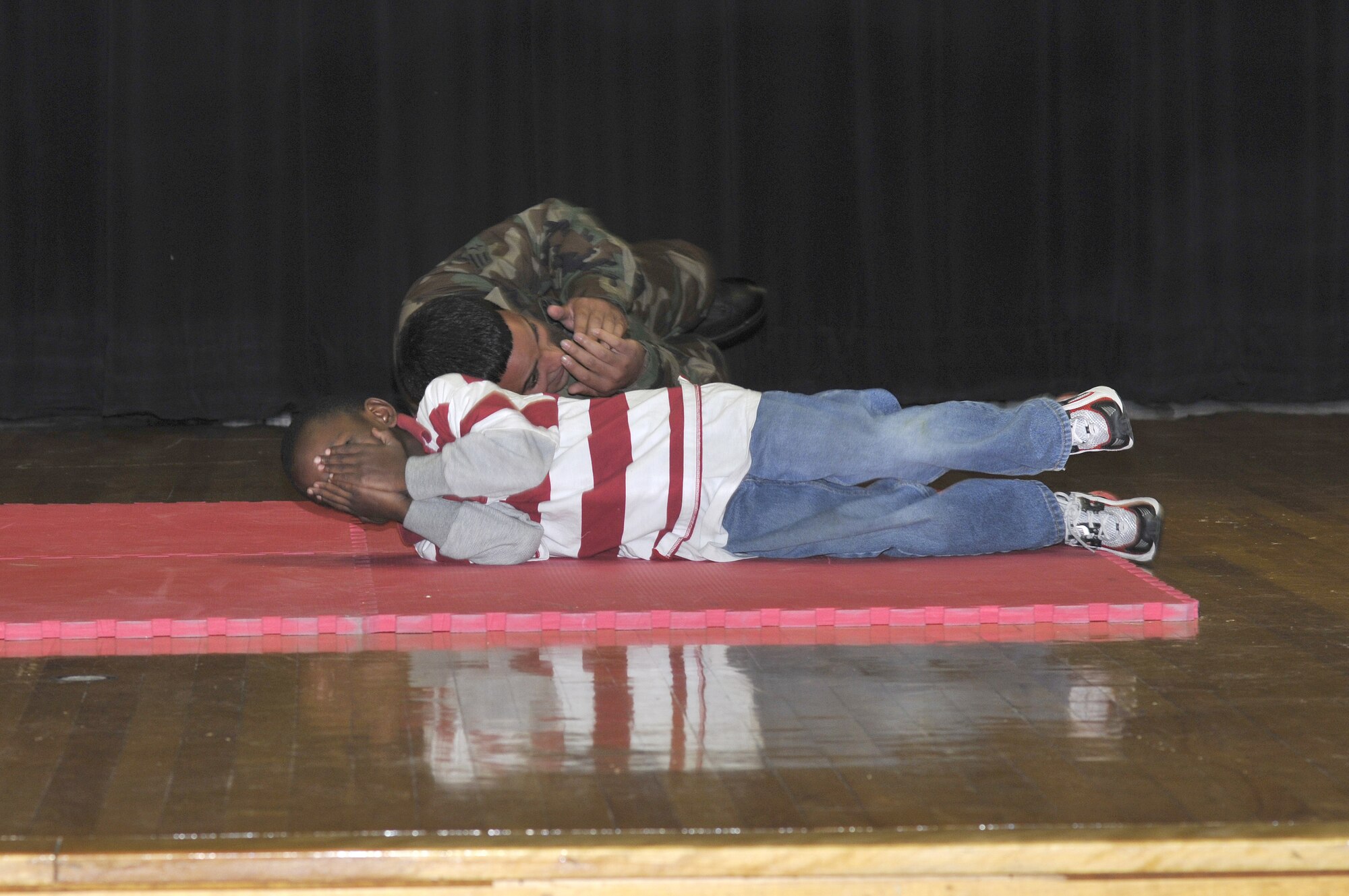 Edward Ector, a first grader at the Atlantis School, shows his fellow students how to “stop, drop and roll” during a demonstration held by the McGuire Fire Department during Fire Prevention Week Oct. 5-11. The firefighters also demonstrated some of their equipment to show the children how they put out fires and teach them what to do if their house is ever on fire.  (U.S. Air Force photo/Kenn Mann)