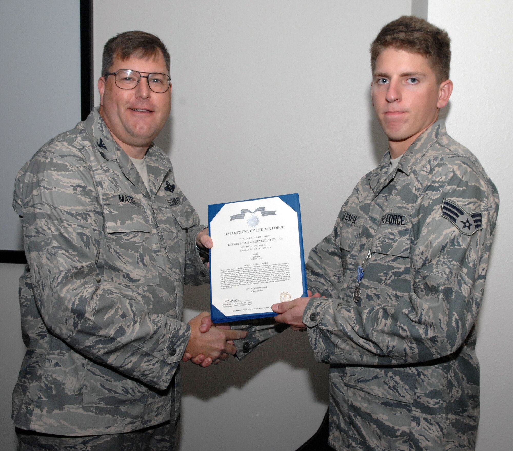 DYESS AIR FORCE BASE, Texas -- Senior Airman Dustin Gillespie, 317th Maintenance Squadron, receives the Air Force Achievement Medal from Col. Bernard Mater, 317th Airlift Group commander, for heroism before departing Dyess for a deployment on Oct. 12.  Five days earlier, Airman Gillespie performed self-aid and buddy care on Bradin Lowe, a toddler who was thrown from a vehicle after an accident despite being in a car seat.  He treated the toddler for shock and a head wound. After treating the toddler, Airman Gillespie also controlled the crowd to allow for ambulance access, and kept the child and his mother calm.  According to Colonel Mater, the timely actions of Airman Gillespie contributed to the well-being of the toddler and prevented his medical condition from becoming life-threatening.  (U.S. Air Force photo by Staff Sgt. Connor Estes).      
