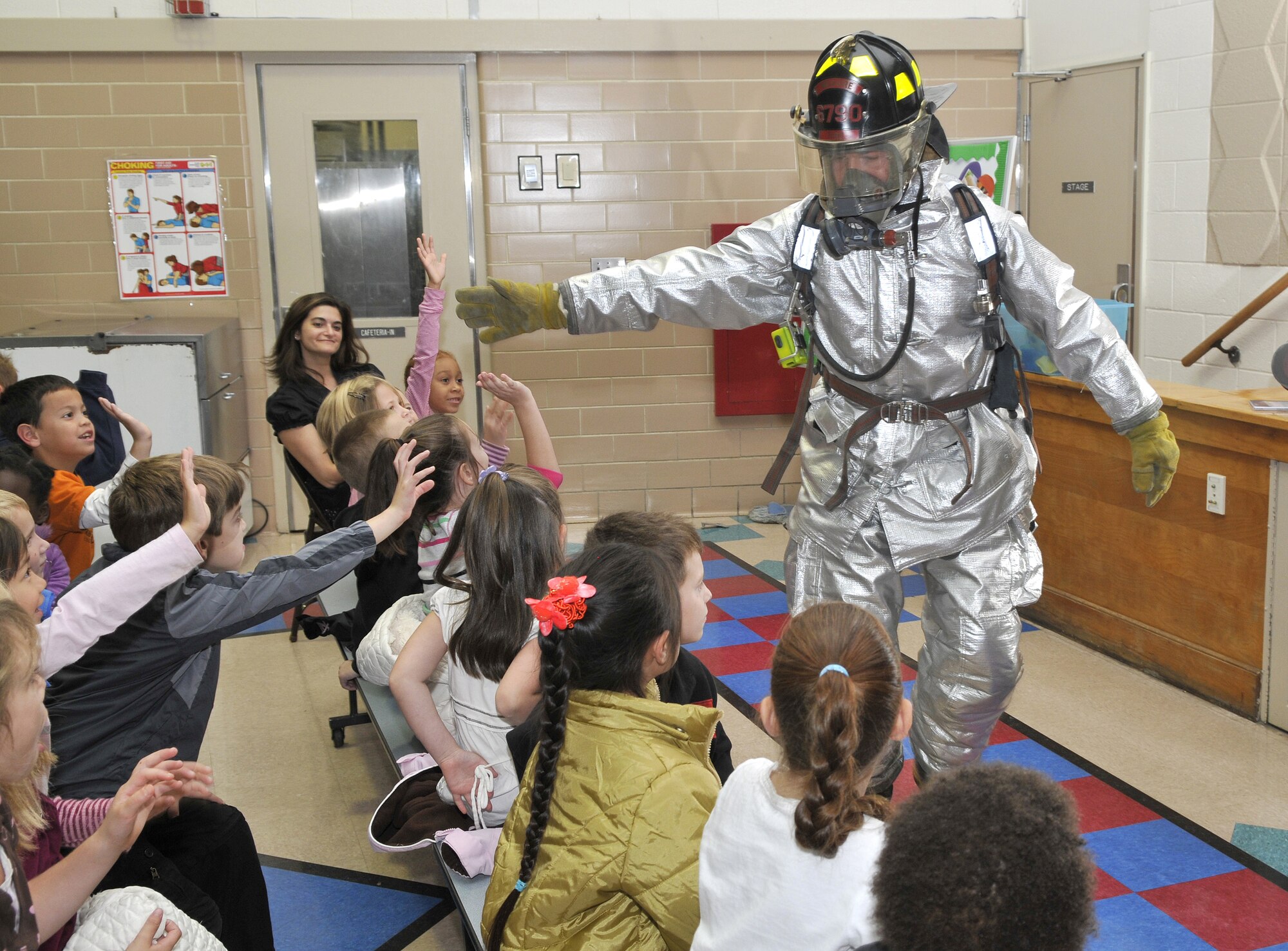 Airman 1st Class Jeffrey Hutcheson, a firefighter with the 305th Civil Engineer Squadron, gives "high fives" to first-grade students at the Atlantis School during Fire Prevention Week events held Oct. 5-11. Airman Hutcheson put on his firefighter’s suit to show the students the equipment firefighters use to put out fires.  The McGuire Fire Department visited the schools to educate children on what to do if their house becomes engulfed in flames. (U.S. Air Force photo/Kenn Mann)