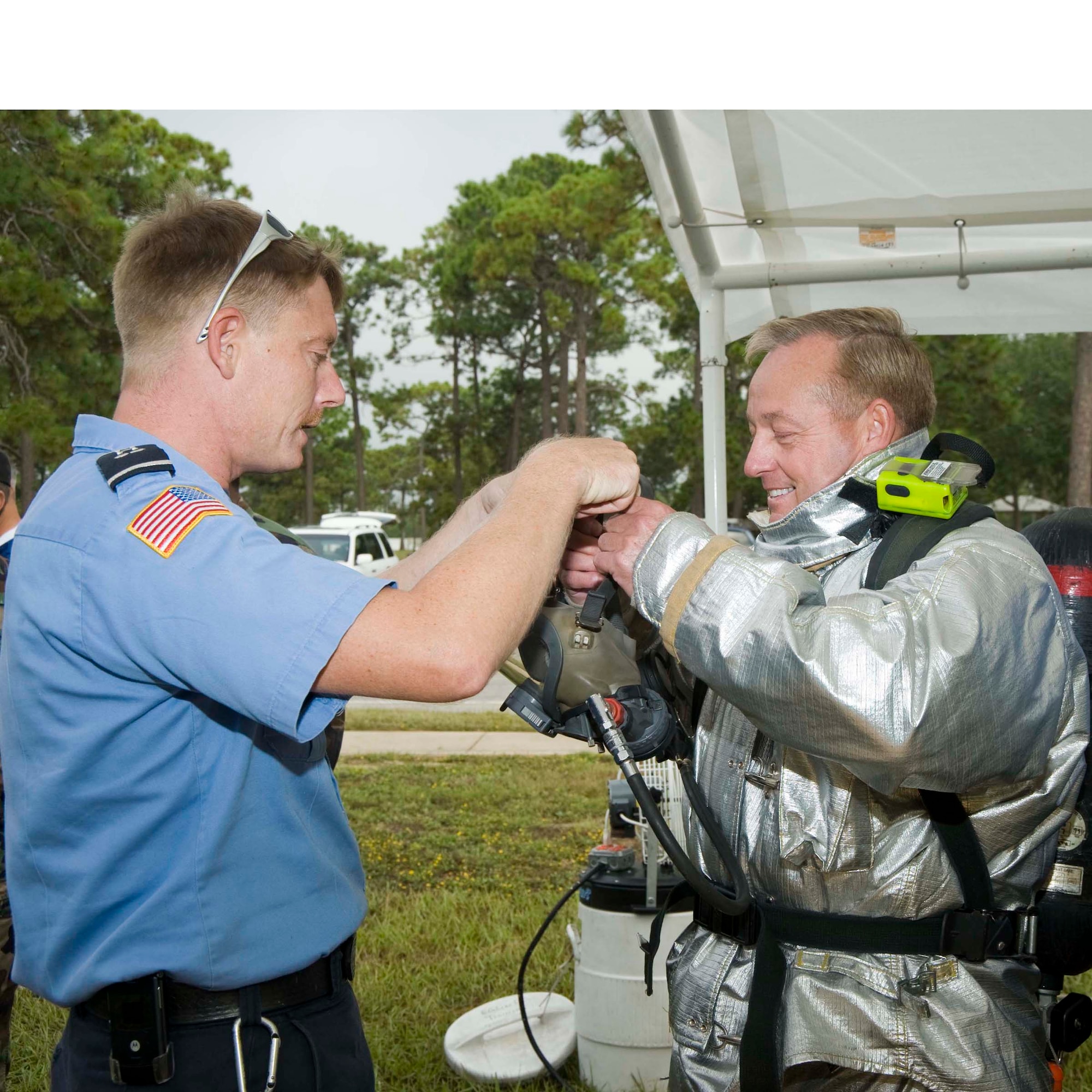 Firefighter Bruce Ehrenberger helps Col. Stephen O'Rear, 96th Communications Group commander, dress out to participate in Fire & Emergency Services Commanders Challenge Oct. 10, where the commanders rescued a "victim" from a smoke-filled house. The 96th CG won the challenge with a record-setting time of 1 minute and 46 seconds. (USAF photo by Bruce Hoffman)

