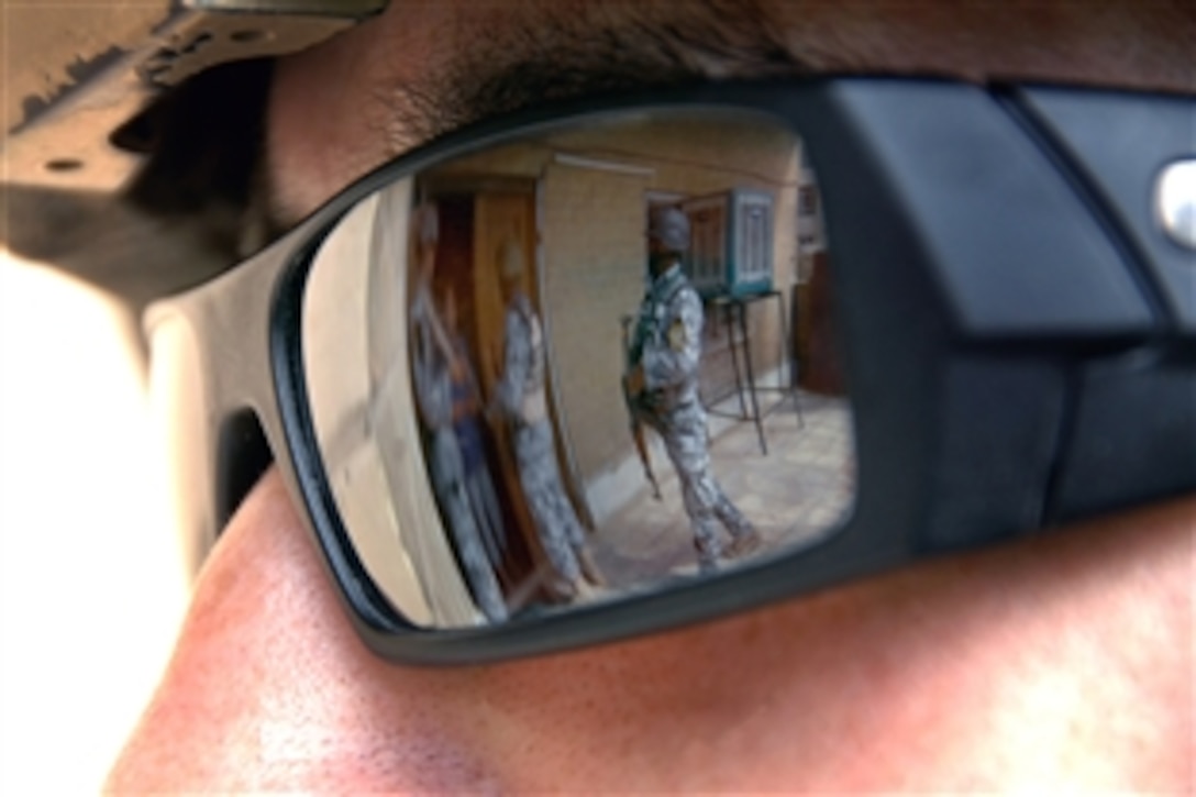 U.S. Army Sgt. Carlos Herrera watches as Iraqi National Police engage local citizens during phase one of Operation Patriot Enforcement, a cordon and soft knock of a neighborhood in Muhallah 902, Wehda, eastern Baghdad, Iraq, Oct. 9, 2008. The soldiers are assigned to Apache Troop, 3rd Squadron, 89th Cavalry, 4th Brigade Combat Team, 10th Mountain Division.
