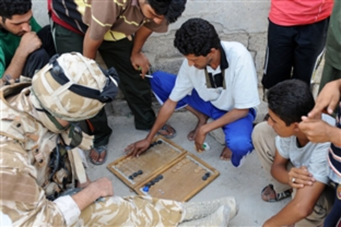 Robert Seely, a British soldier with the 15th Physiological Operations Group, plays Backgammon with residents in Basra, Iraq, Oct. 10, 2008. 