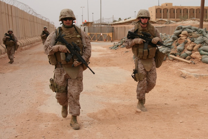 Sgt. Joan A. Ferreira (left), a 24-year-old team leader with Task Force Military Police, Multi-National Force-West, departs Combat Outpost Trebil on patrol with his Marines Oct. 15.  Ferreira is a New York City police officer and Individual Ready Reservist currently on one-year mobilization orders. ::r::::n::