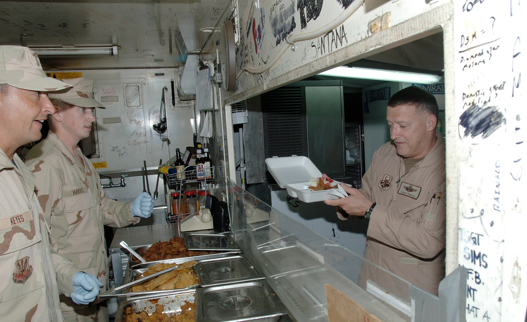 SOUTHWEST ASIA -- Master Sgt. Robert Keyes and Staff Sgt. Adam Harris from the 380th Expeditionary Force Support Squadron serve some food to Air Force Central Command Commander Lt. Gen. North at Roy's Diner Aug. 31.  Roy's Diner has been the flightline dining facility for hungry 380th personnel for four years. (U.S. Air Force photo/Tech. Sgt. Christopher A. Campbell)(released)