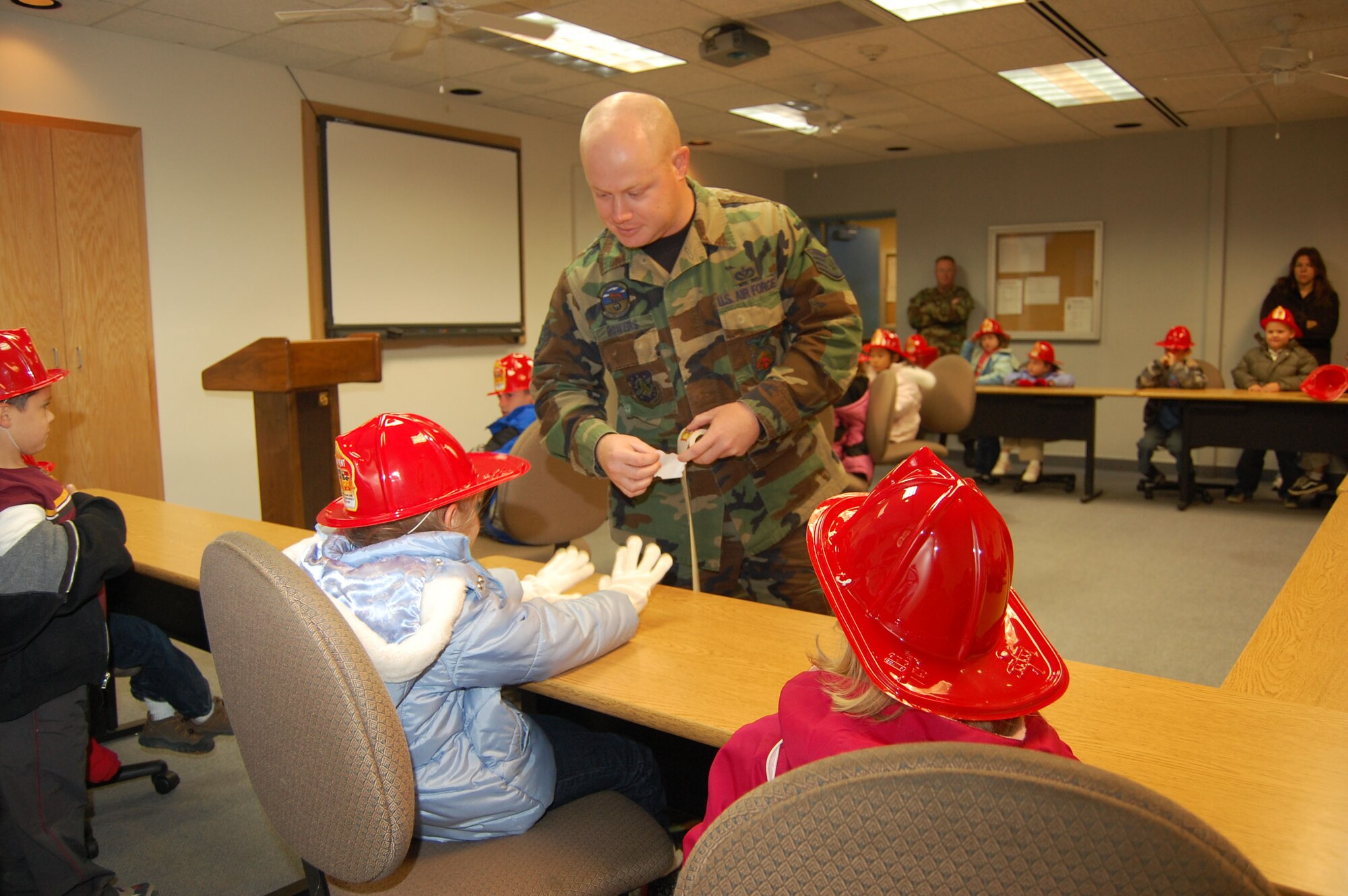 Staff Sgt. Cory Bowers, 341st Civil Engineer Squadron fire crew chief, passes out honorary firefighter stickers to kindergartners from Loy Elementary School during a tour. The tour was held during Fire Prevention Week. (U.S. Air Force photo/Senior Airman Emerald Ralston)