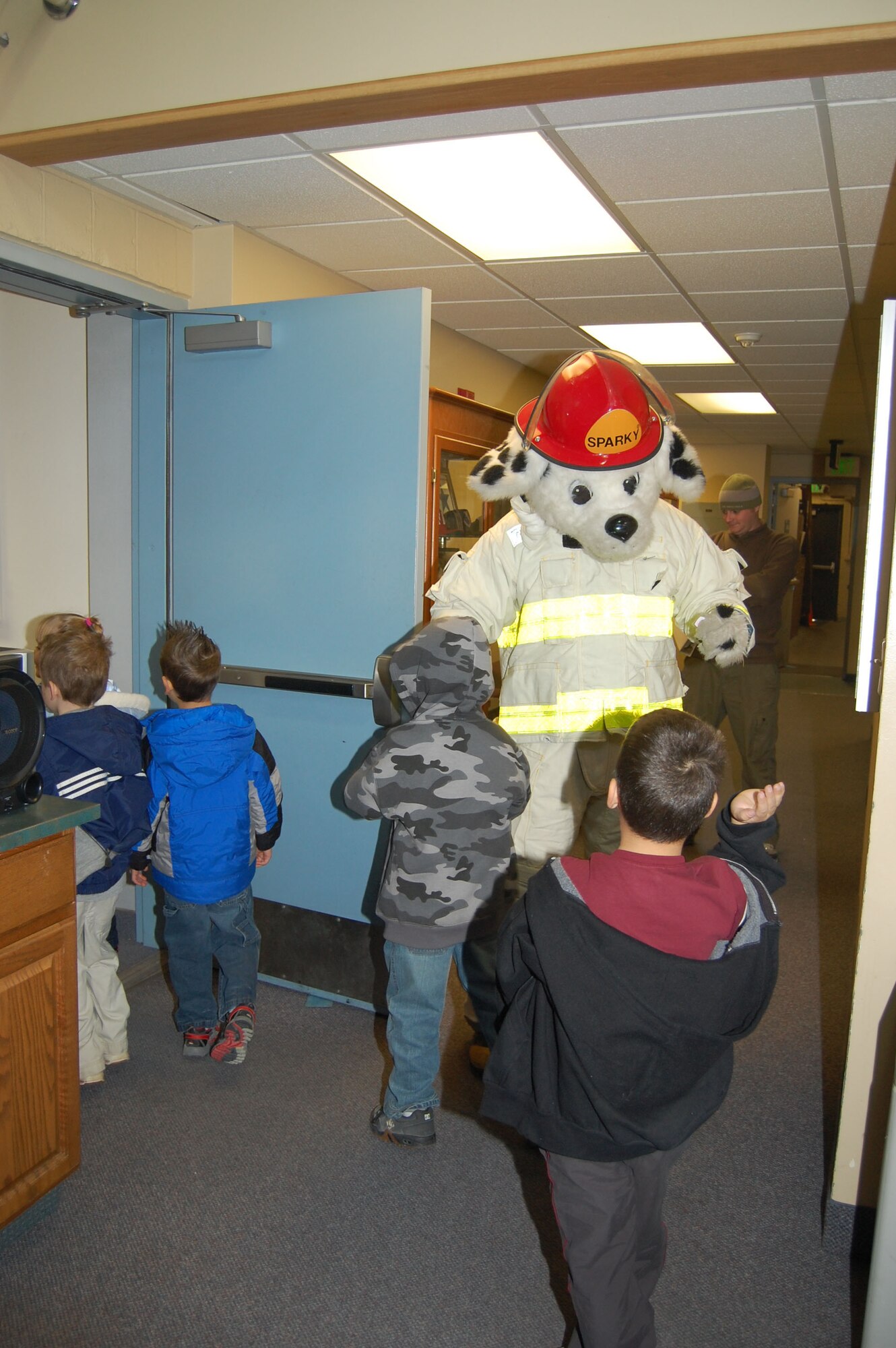 Sparky the Fire Dog high-fives kindergartners as they go through a tour of the fire department Oct. 9. The tour was held for Loy Elementary students during Fire Prevention Week. (U.S. Air Force photo/Senior Airman Emerald Ralston)