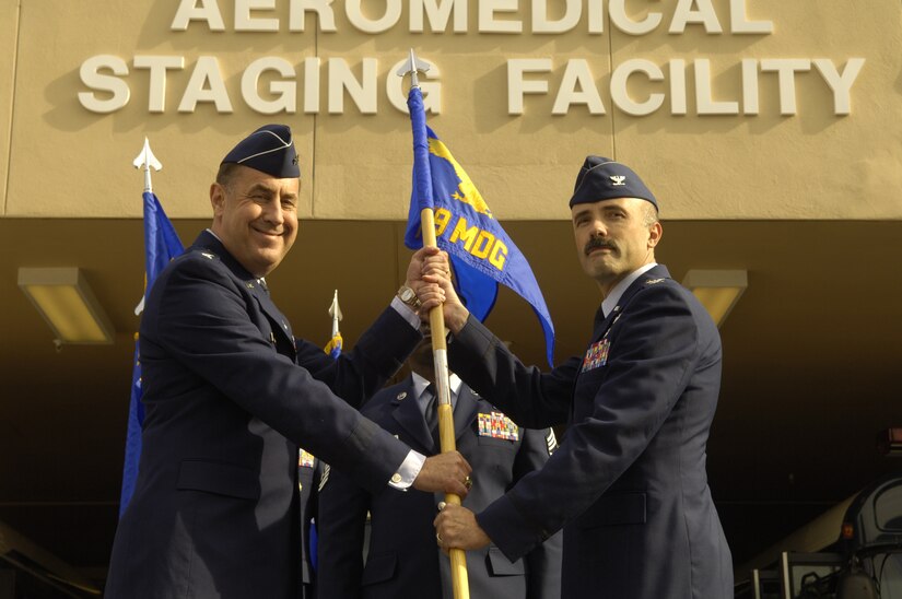 Maj. Gen. Gar S. Graham, 79th Medical Wing commander, passes the guidon to Col. Robert I. Miller, 779th Medical Group commander, as part of the deactivation of the 79th Medical Group and the activation of the 779th Medical Group on Oct. 9 at Andrews. Included in the ceremony was a ribbon cutting signifying the reopening of the Aeromedical Staging Facility.