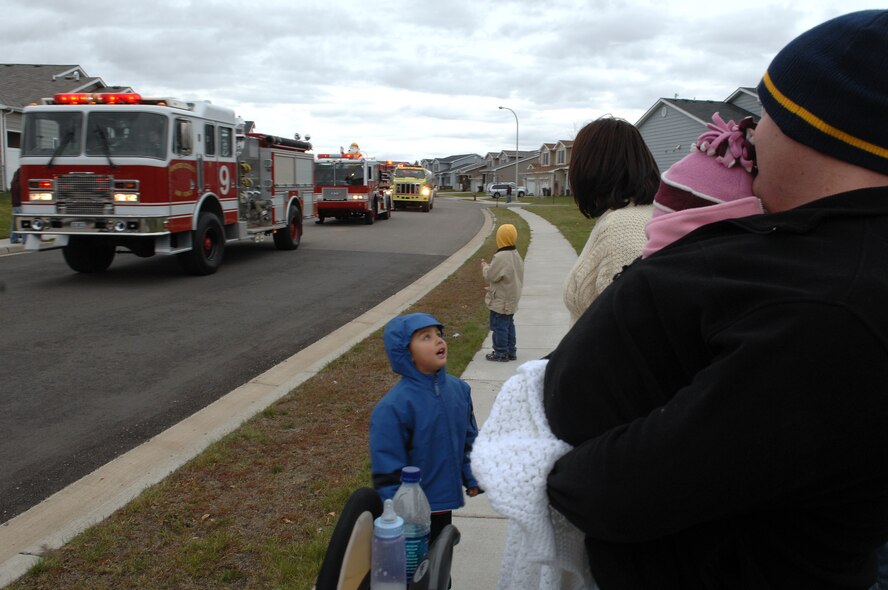 MINOT AIR FORCE BASE, N.D. – Staff Sgt. Charles Waters, 5th Aircraft Maintenance Squadron, and his family brave the cool evening to watch the 5th Civil Engineer Squadron firefighters and their emergency services vehicles pass through base housing here Oct. 10 during the 2008 Fire Prevention Week parade.  The purpose of the first-ever event is to remind base residents to take proper precautions to help prevent fires and to have a plan in the event of a fire.  Fire Prevention Week took place nationwide Oct. 5 to 11. (U.S. Air Force photo by Senior Airman Kelly Timney)
