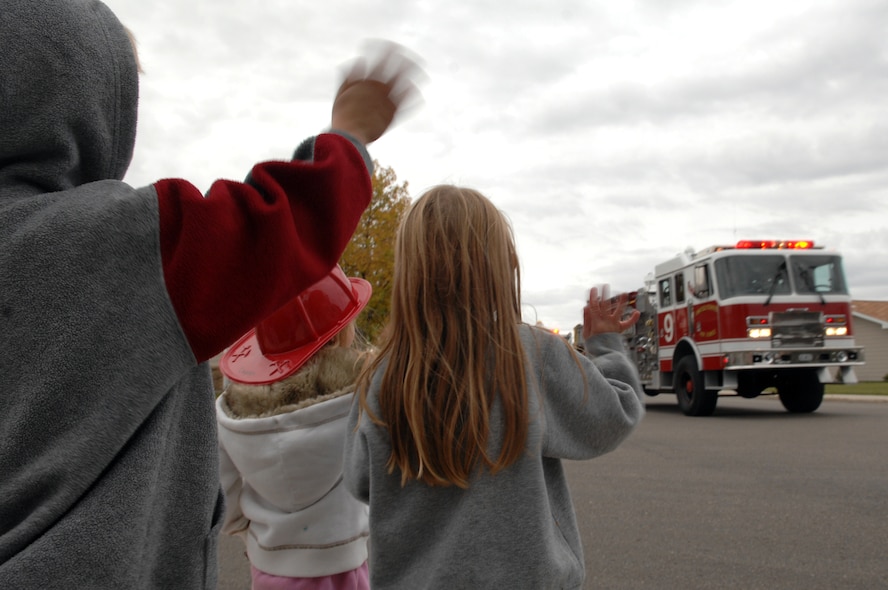 MINOT AIR FORCE BASE, N.D. -- A group of children wave to the 5th Civil Engineer Squadron firefighters as their emergency services vehicles pass through base housing here Oct. 10 during the 2008 Fire Prevention Week parade.  The purpose of the first-ever event is to remind base residents to take proper precautions to help prevent fires and to have a plan in the event of a fire.  Fire Prevention Week took place nationwide Oct. 5 to 11. (U.S. Air Force photo by Senior Airman Kelly Timney)