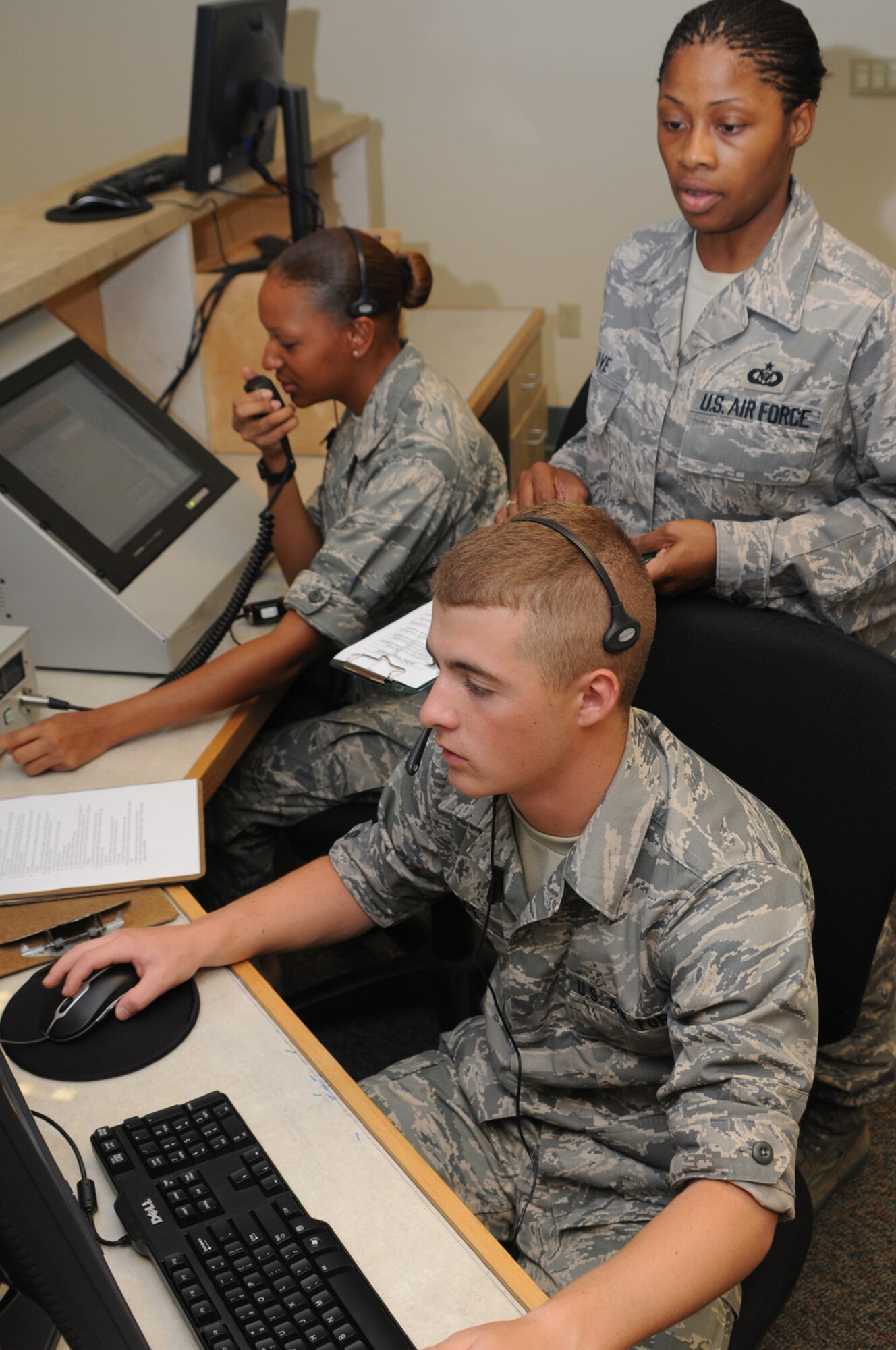 Staff Sgt. Betty Love observes two of her students, Airmen Basic Joseph Pope and Celia Brown, using fingers-on-glass computers to maintain flight schedules.  (U.S. Air Force photo by Kemberly Groue)