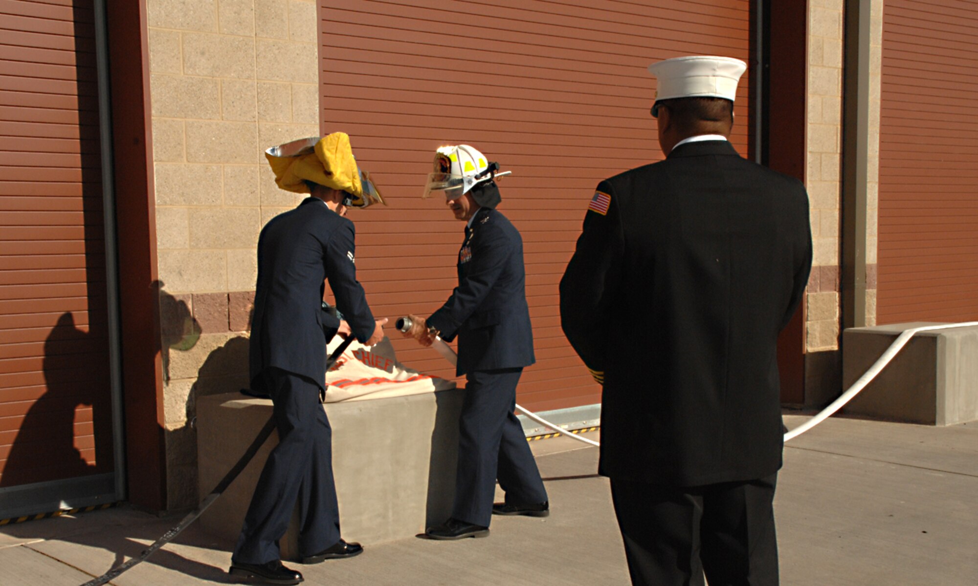 Mr. Dean DeGuzman, assistant chief of operations assigned to the 49th Civil Engineer Squadron, looks on as Airman 1st Class Kenneth Nixon, firefighter assigned to the 49th CES and Col. Jeff Harrigian, 49th Fighter Wing commander, disconnect the hose coupling of the new Fire Station 1 at Holloman Air Force Base, N.M., October 9. (U.S. Air Force photo/ Senior Airman Tiffany Trojca)