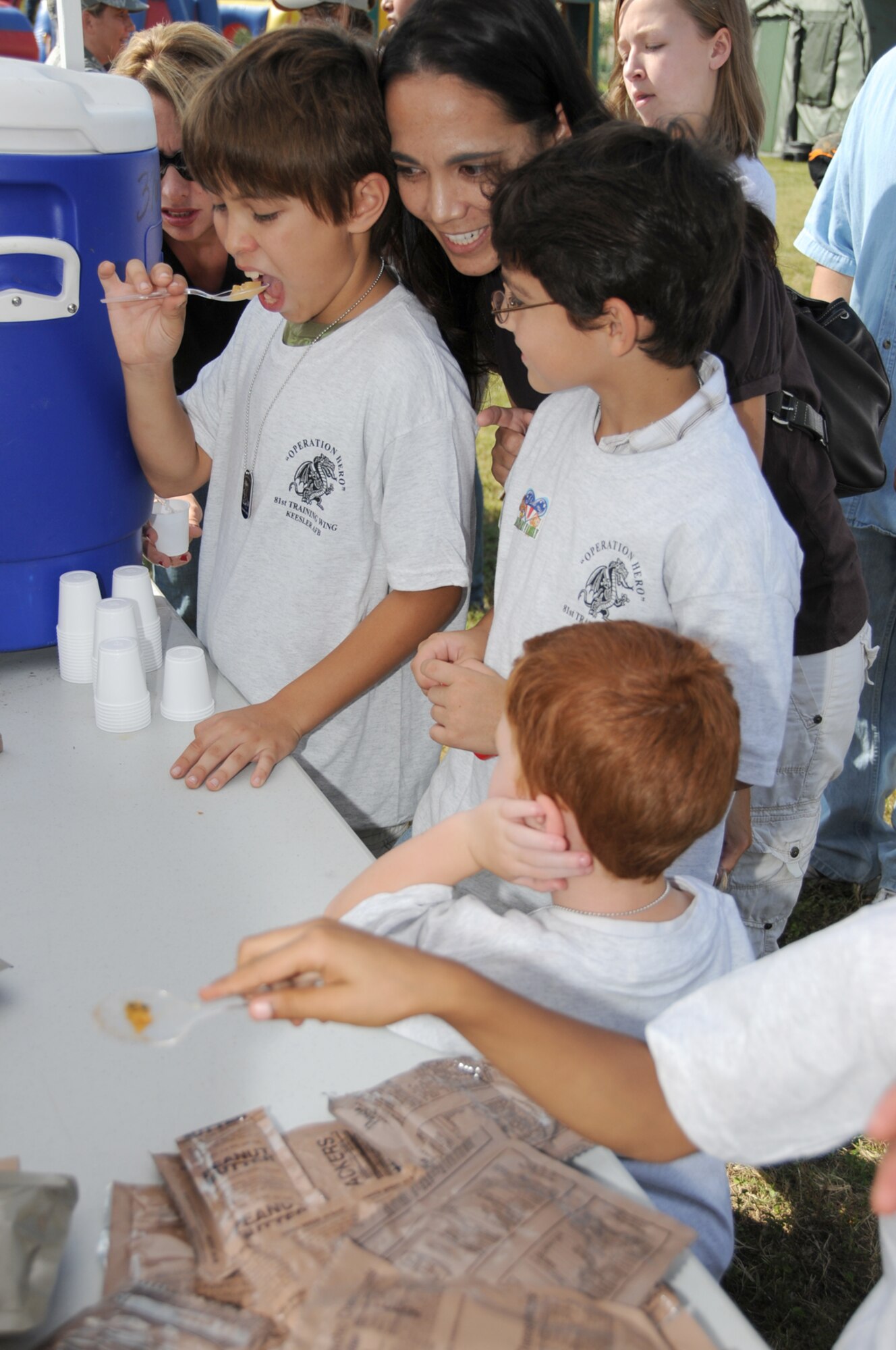 Ten-year-old Justin Clevenger samples meals-ready-to-eat at Operation Hero with his mom, Maj. Margaret Clevenger, 81st Surgical Operations Squadron, and brother Noah, 8.  (U.S. Air Force photo by Kemberly Groue)