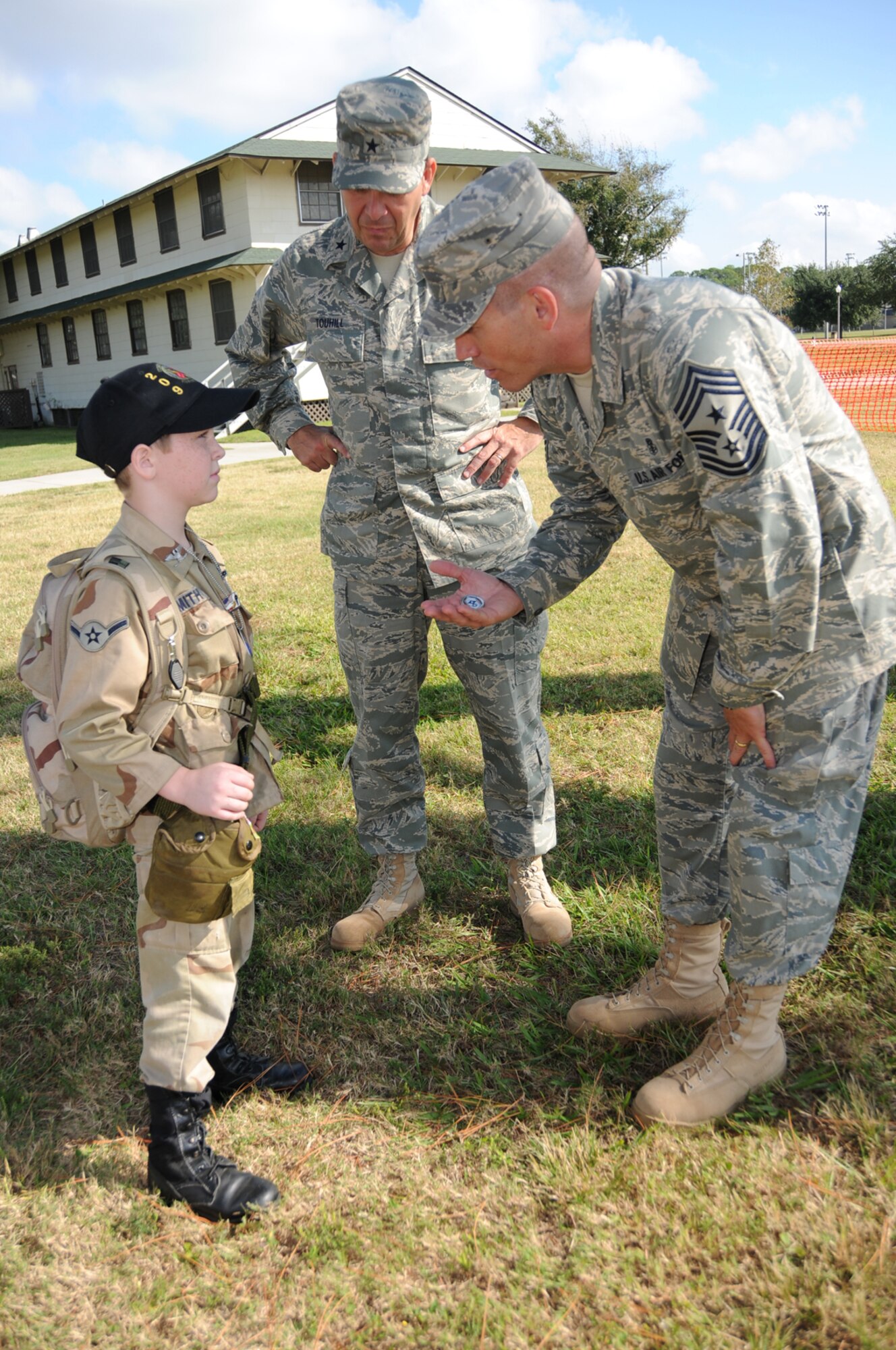 Eight-year-old John Smith receives an 81st Training Wing coin from Chief Master Sgt. Alex Perry, command chief, as Brig. Gen. Greg Touhill, wing commander, looks on.  John’s uncle, Chief Master Sgt. Hurtis Nall, helped his nephew make the uniform with items that once belonged to him.  Chief Nall is assigned with the Mississippi Air National Guard in Gulfport.  (U.S. Air Force photo by Kemberly Groue)