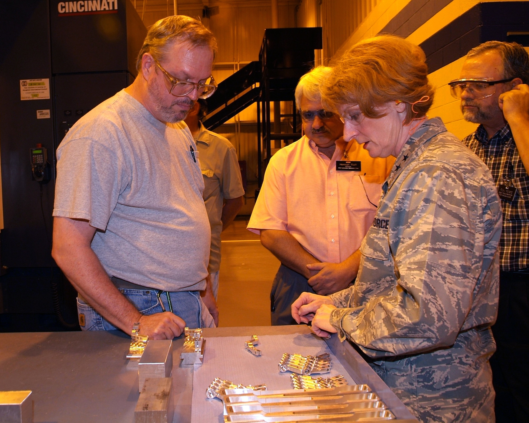 Gaylord Reule, machinist, with Herman Raiff, 402nd CMXG director, and Ricky Holland, machine shop flight chief, looking on, discusses with Maj. Gen. Polly Peyer, Center commander,how the aileron actuator levers for the T-38 Talon aircraft are manufactured in the machine shop. U. S. Air Force photo by Tommie Horton