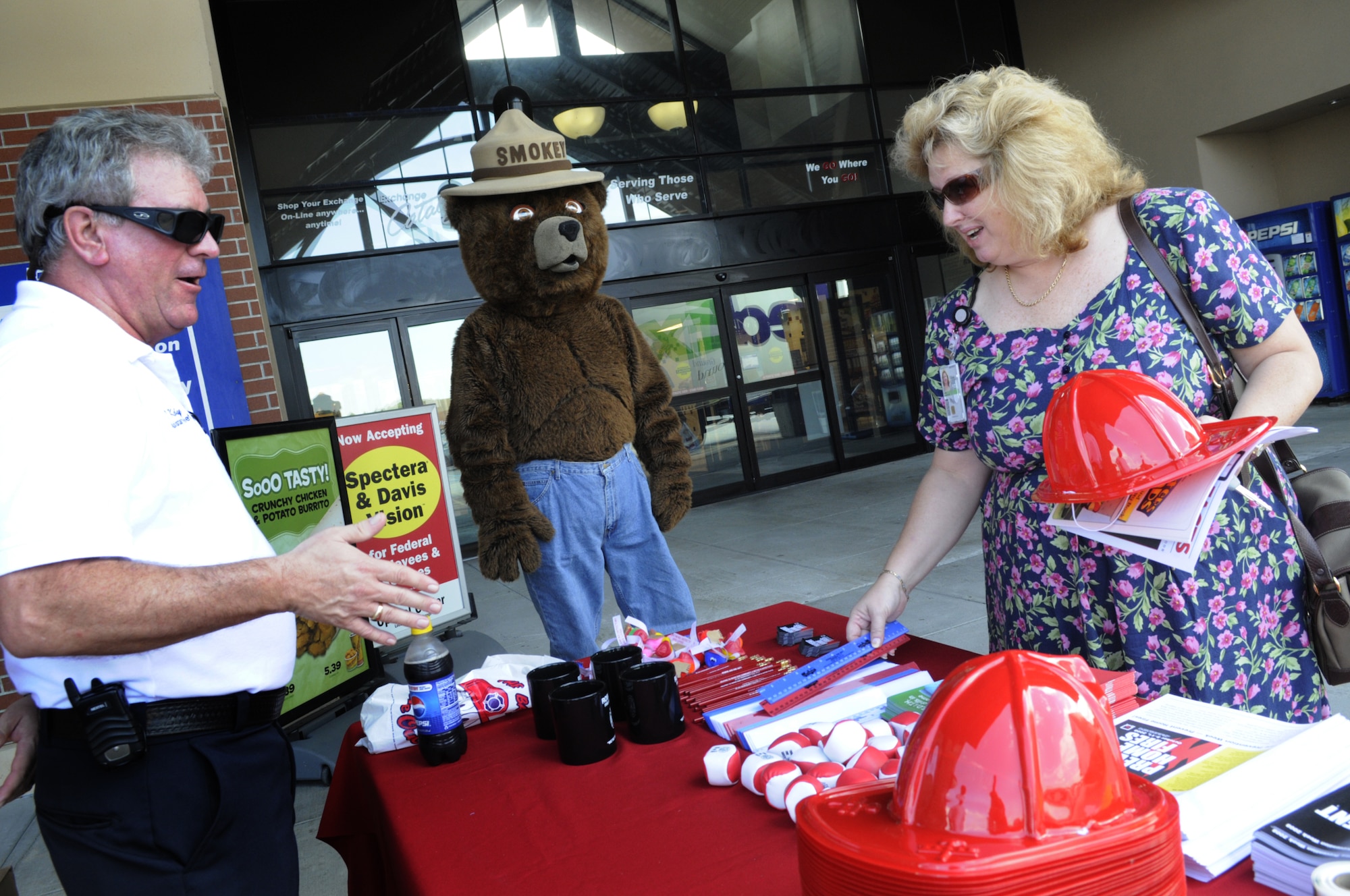 Robins firefighters spent time on base spreading the word on fire prevention this week. Tom Kennedy and Smokey Bear visit patrons at the BX Oct. 6 as Sheryl Winn helps herself to some free literature and gifts. U. S. Air Force photo by Sue Sapp