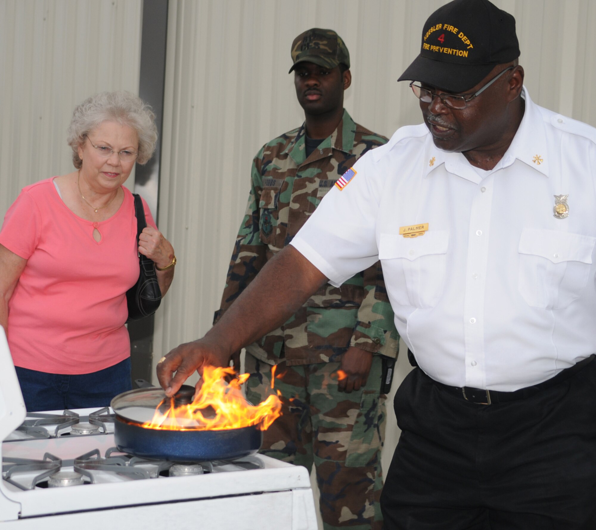 Below, retiree spouse Jean Roush of Gautier and Staff Sgt. Commie Hobbs from the fire department watch James Palmer, assistant fire prevention chief, extinguish a pan fire during a demonstration in front of the base exchange, Oct. 6.  (U.S. Air Force photo by Kemberly Groue)