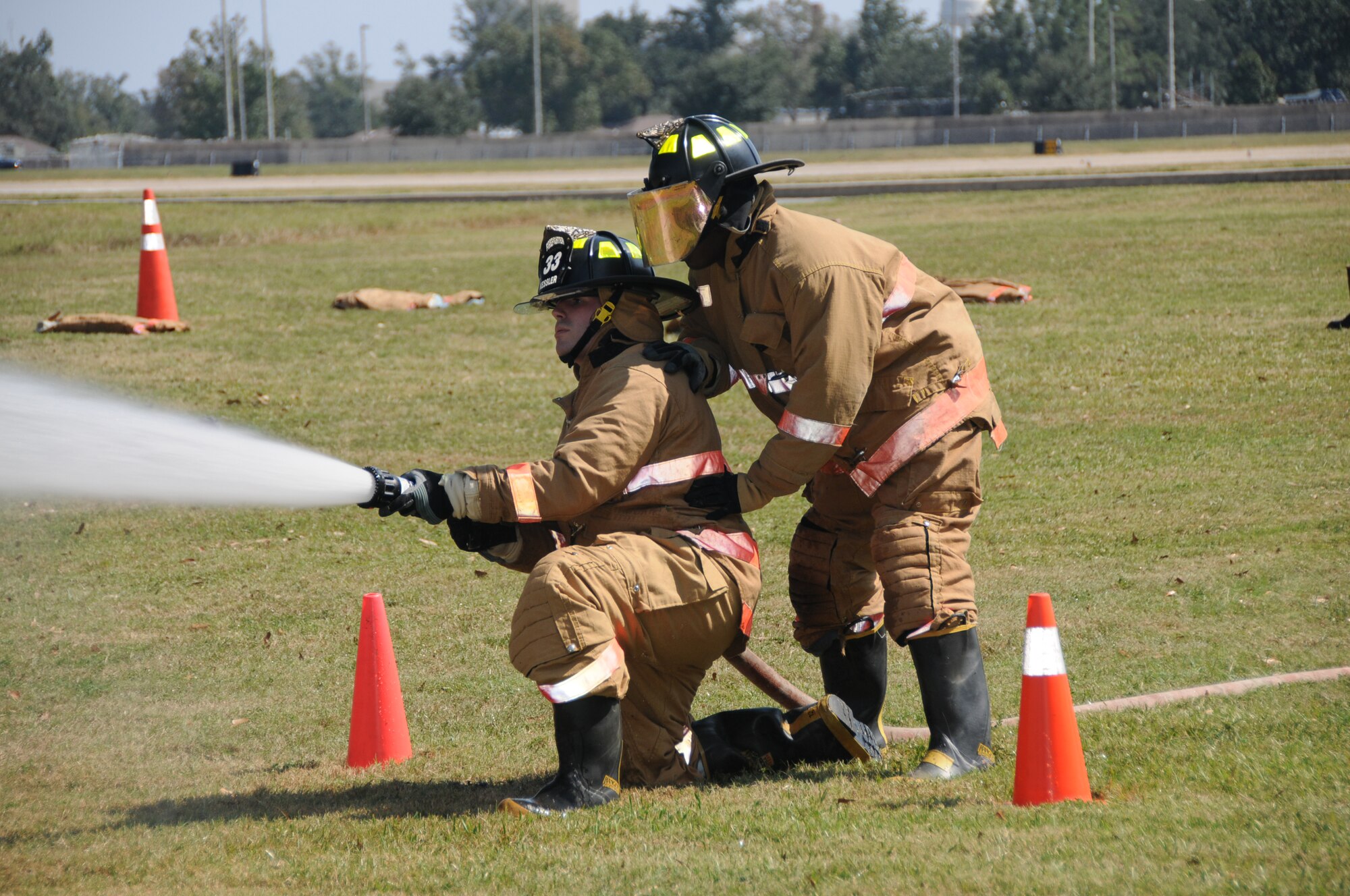 Left, Staff Sgt. Christopher Judge, left, and Capt. Jer-maine Jordan, 333rd Train-ing Squadron, compete in Friday’s fire muster’s firefighter challenge, in which they had to don bunker gear, connect the hose and hit targets with the spray.  (U.S. Air Force photo by Kemberly Groue)