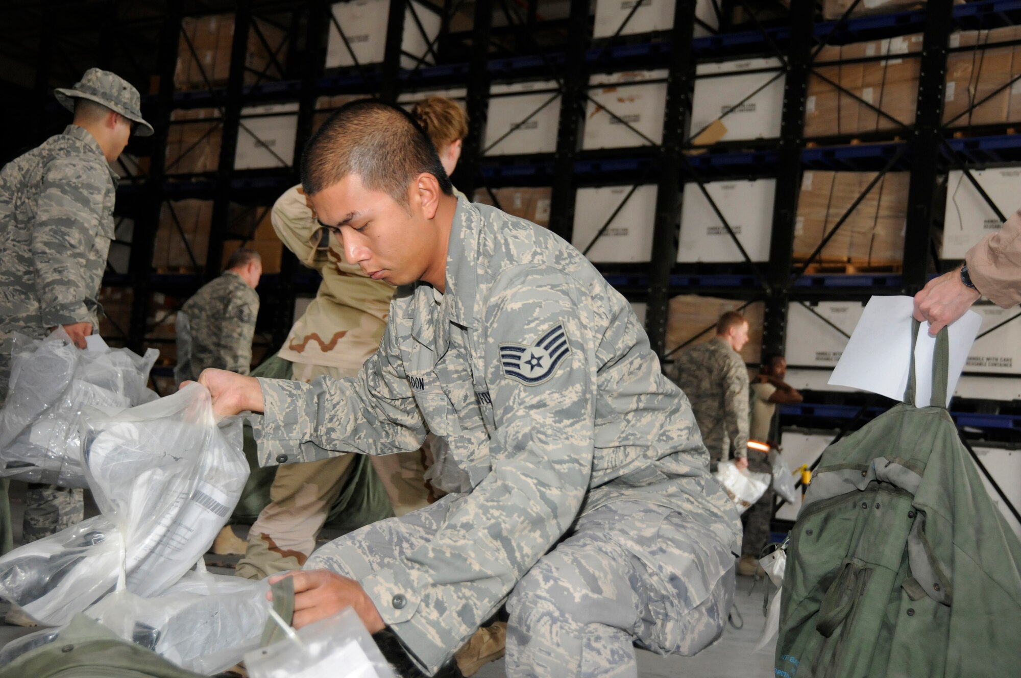 Staff Sgt. Paul Batoon, 379th Expeditionary Mission Support Group, checks the inventory number on his two pair of over boots, October 15, 2008, at an undisclosed air base in Southwest Asia.  Chemical warfare bags and boots were issued to all base personnel as part of a base defense exercise.  Sergeant Batoon, a native of Pearl City, Hawaii, is deployed from Hickam Air Force Base, Hawaii, in support of Operations Iraqi and Enduring Freedom and Joint Task Force-Horn of Africa.  (U.S. Air Force photo by Tech. Sgt. Michael Boquette/Released)
