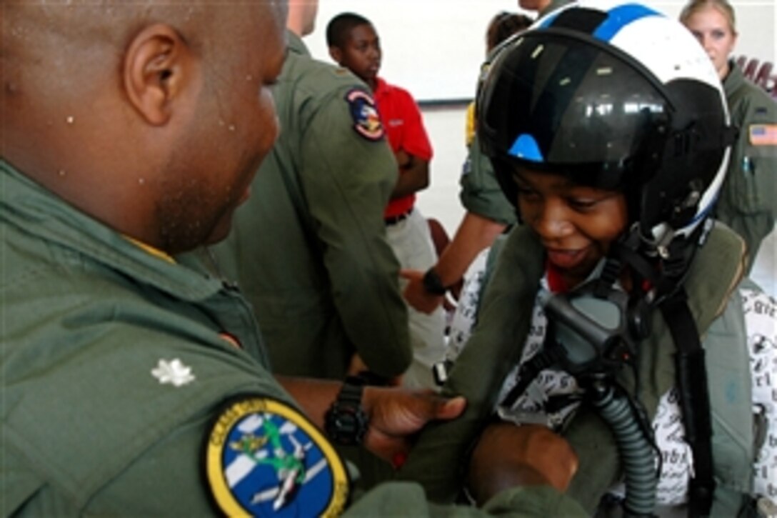 U.S. Navy Cmdr. Willie "BBO" Billingslea, commanding officer of the "Warbucks" from Training Squadron 4, places a flight helmet on a female 8th-grade student from Tuskegee Middle School after speaking to hundreds of students on the importance of goal setting and his experiences as a naval aviator, Tuskegee, Ala., Oct. 9, 2008.