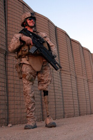 Corporal Garrett S. Jones, an amputee who was injured in 2007 by an insurgent’s bomb during his unit’s deployment to Iraq, stands by protective barriers before heading off to travel to a forward operating base.